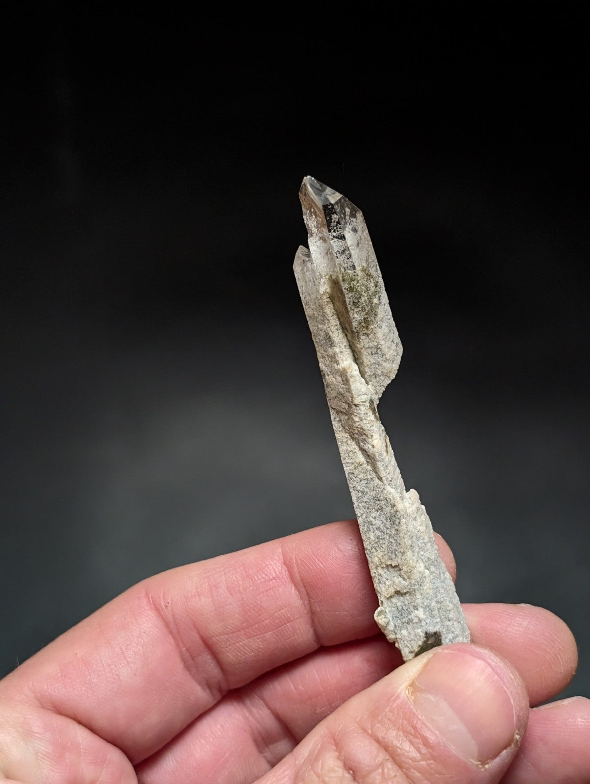 A translucent, pale gray quartz crystal with a pointed tip and natural striations.