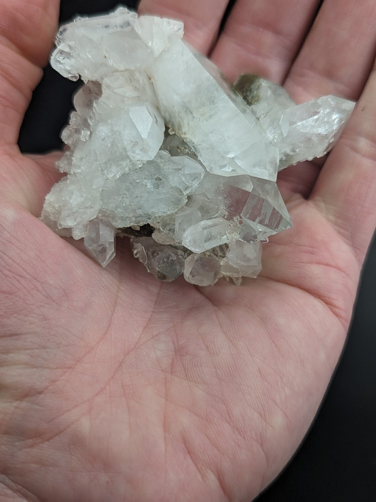 A cluster of clear, translucent quartz crystals with sharp, faceted edges and a natural, irregular formation.