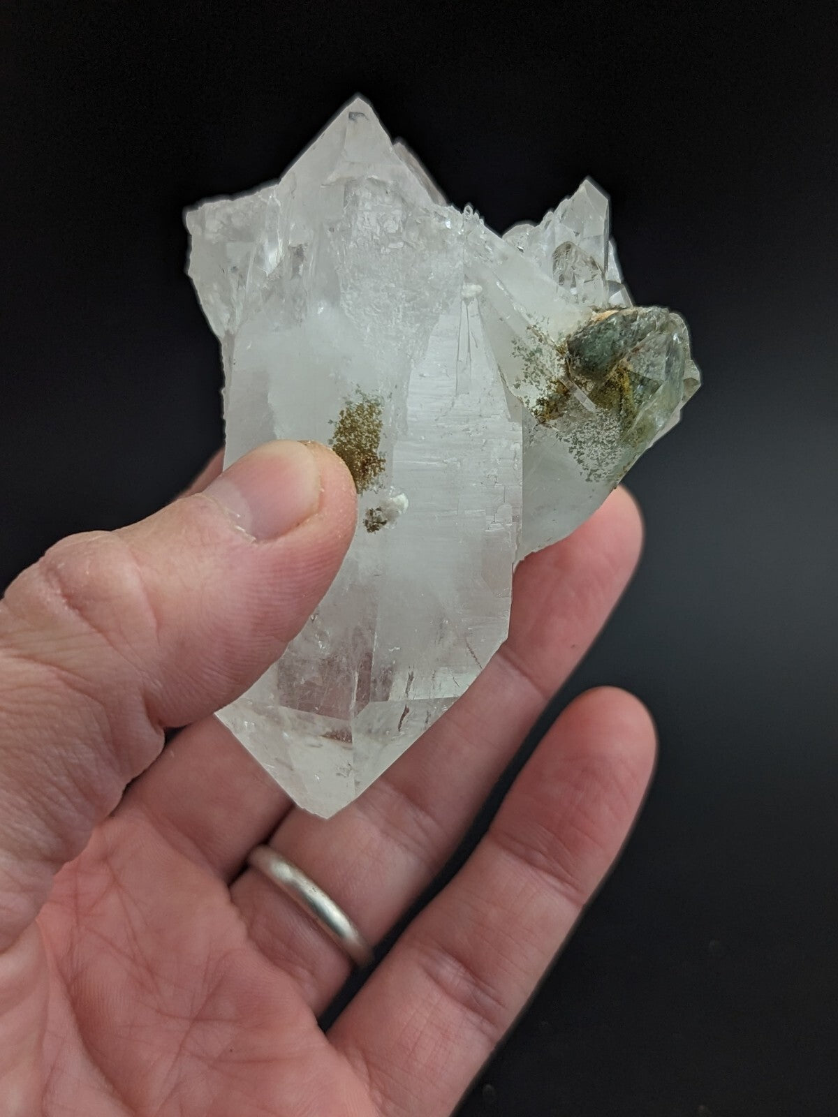 A translucent quartz crystal cluster with clear, faceted points and greenish mineral inclusions.
