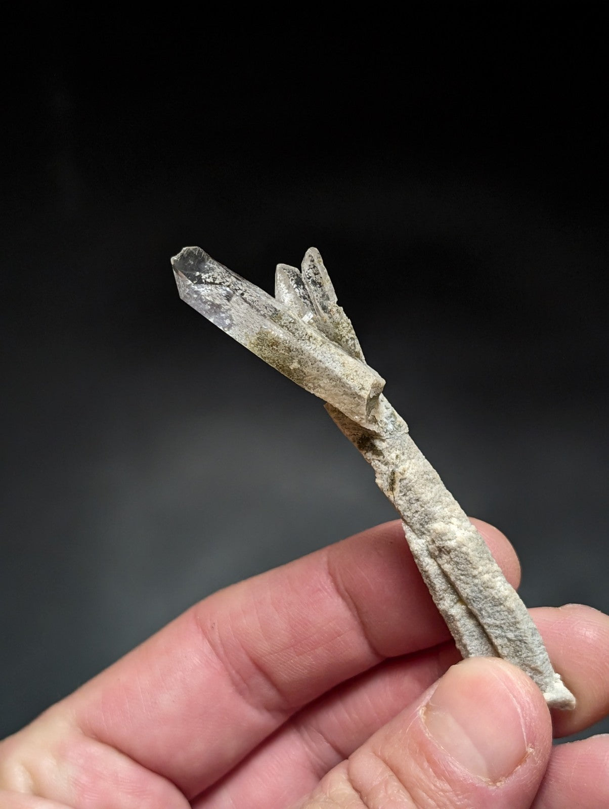 A translucent, pale gray quartz crystal cluster with a rough, textured base and sharp, pointed terminations.