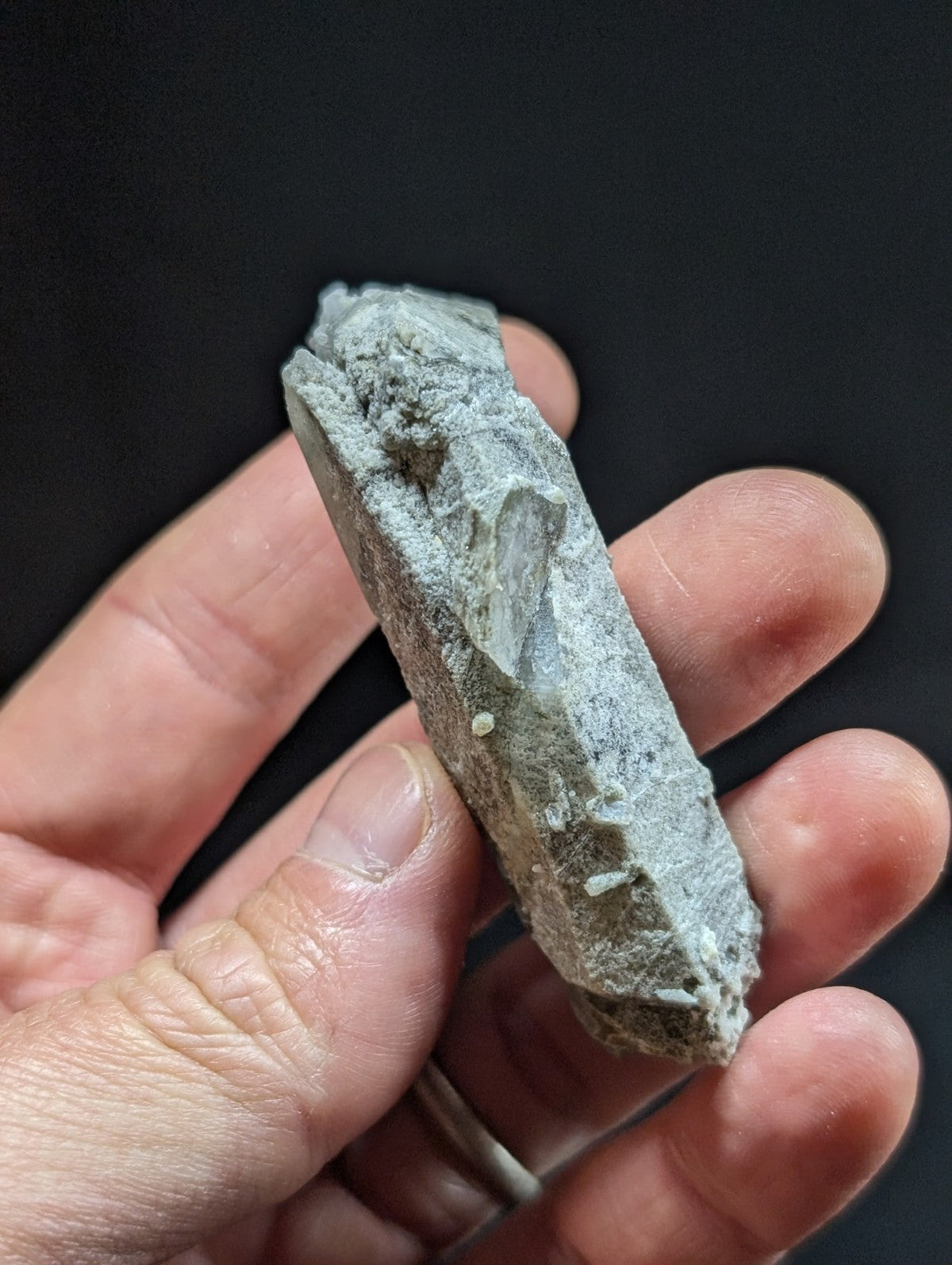 A rough, grayish-white quartz crystal with a jagged surface and visible internal facets.