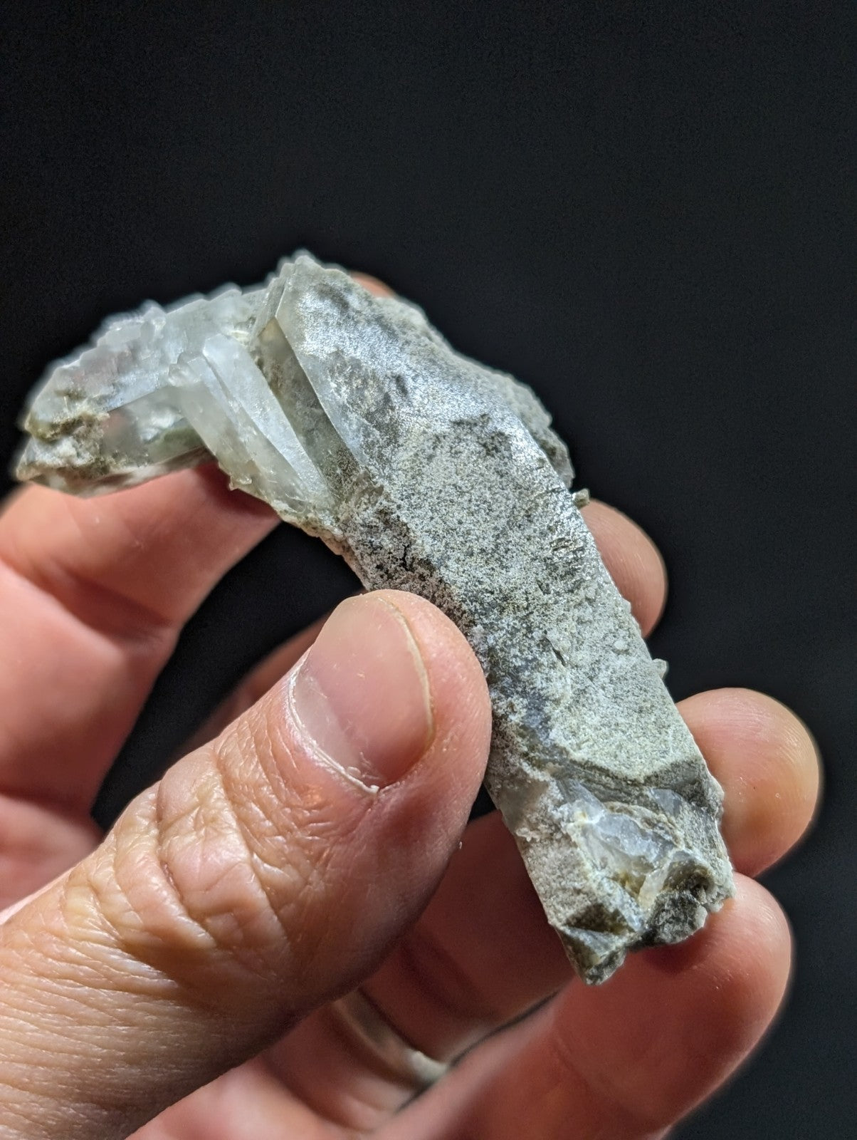 A translucent, grayish-white mineral specimen with crystalline formations and a rough, naturally occurring surface.