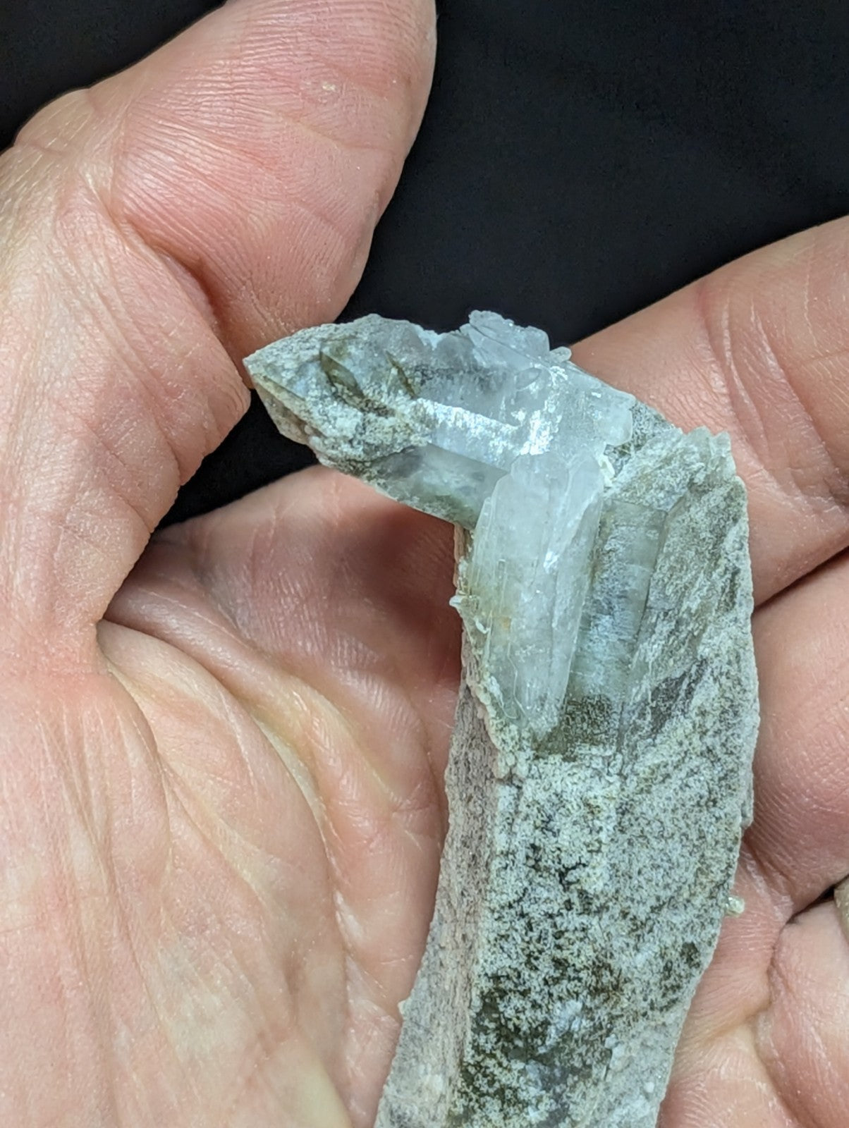 A translucent, pale blue-green quartz crystal formation with a rough, earthy matrix base.