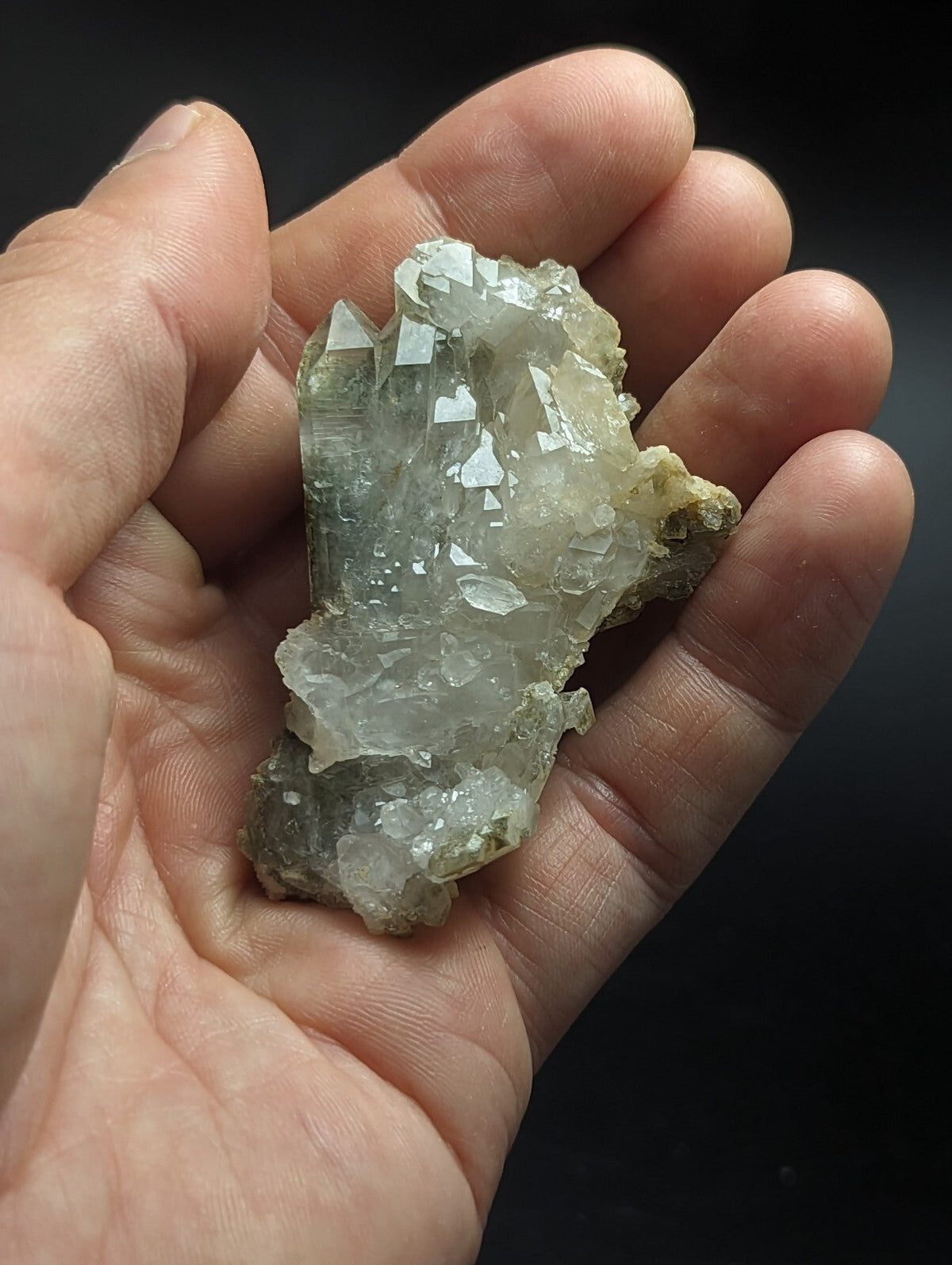 A translucent, pale greenish-white quartz crystal cluster with sharp, faceted points and a rough, natural texture.