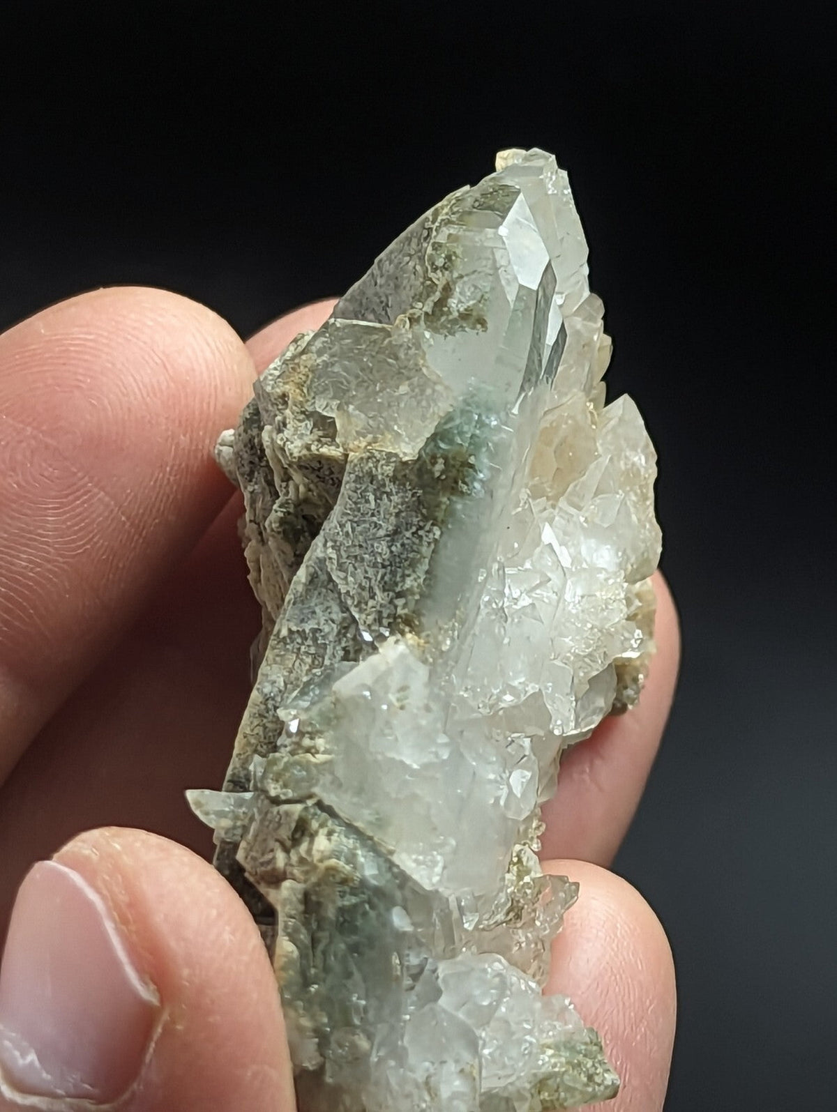 A translucent green and clear quartz crystal cluster with a rough, earthy matrix.