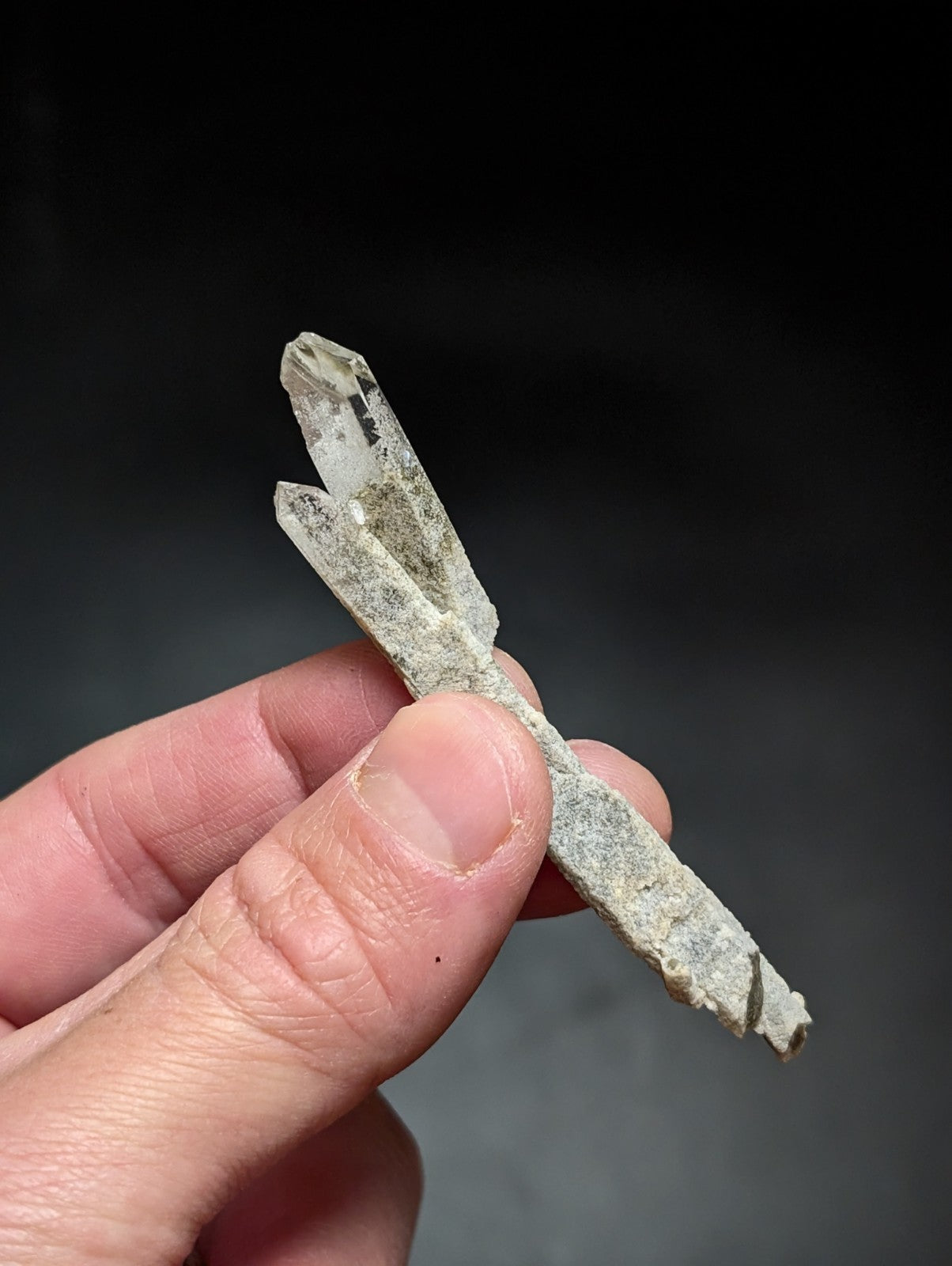 A translucent, pale quartz crystal cluster with a rough, earthy base and sharp, faceted points.