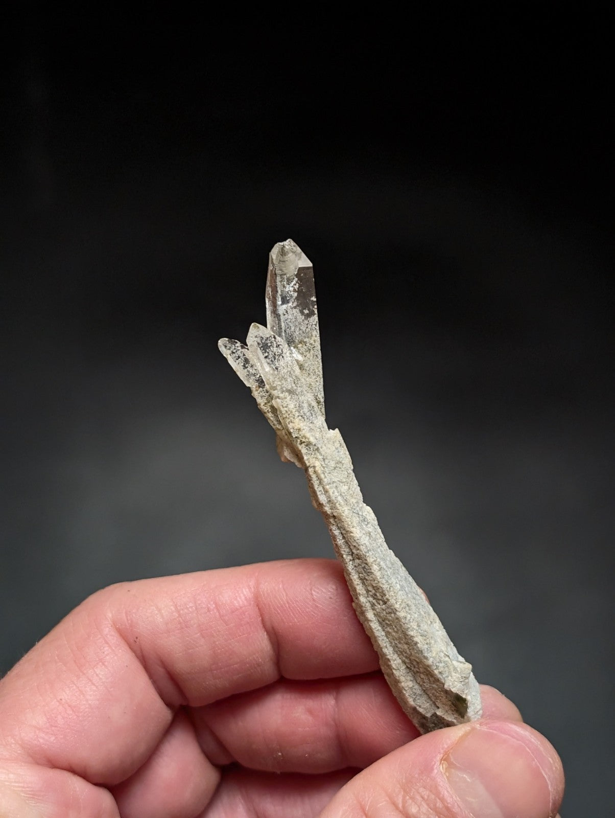 A translucent, clear quartz crystal cluster with a rough, earthy base and sharp, pointed terminations.