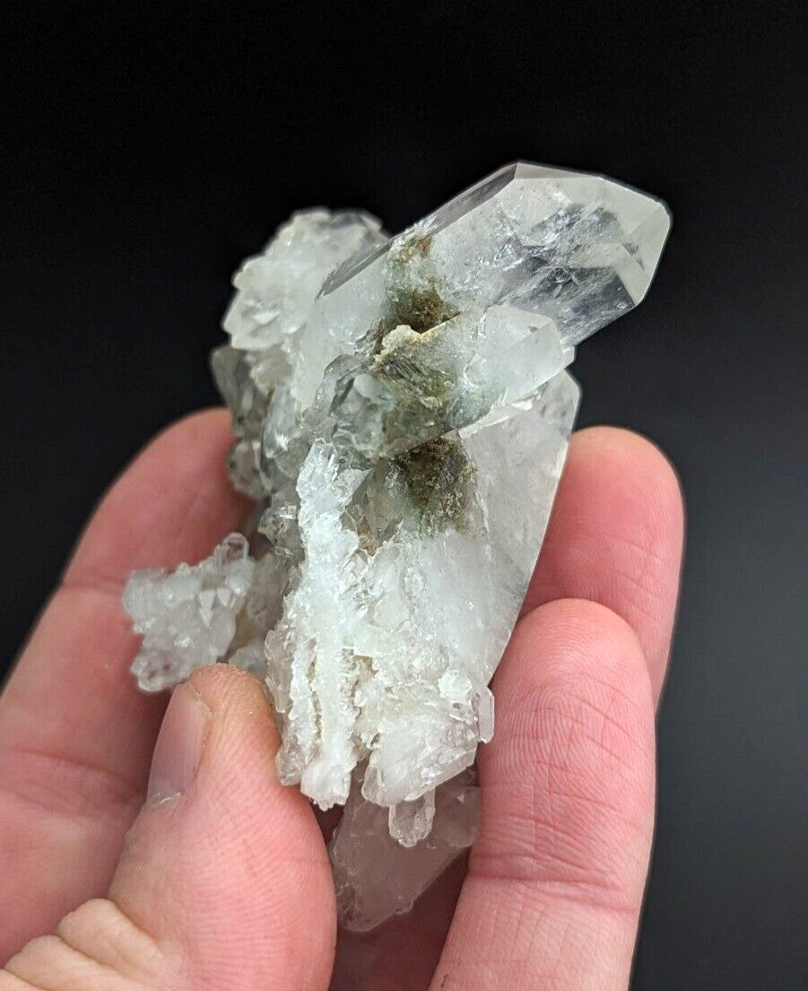 A translucent quartz crystal cluster with clear, faceted points and a central greenish mossy inclusion.