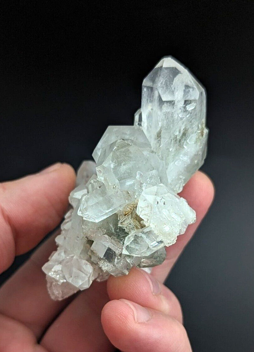 A translucent, pale green quartz crystal cluster with sharp facets and a natural, earthy base.