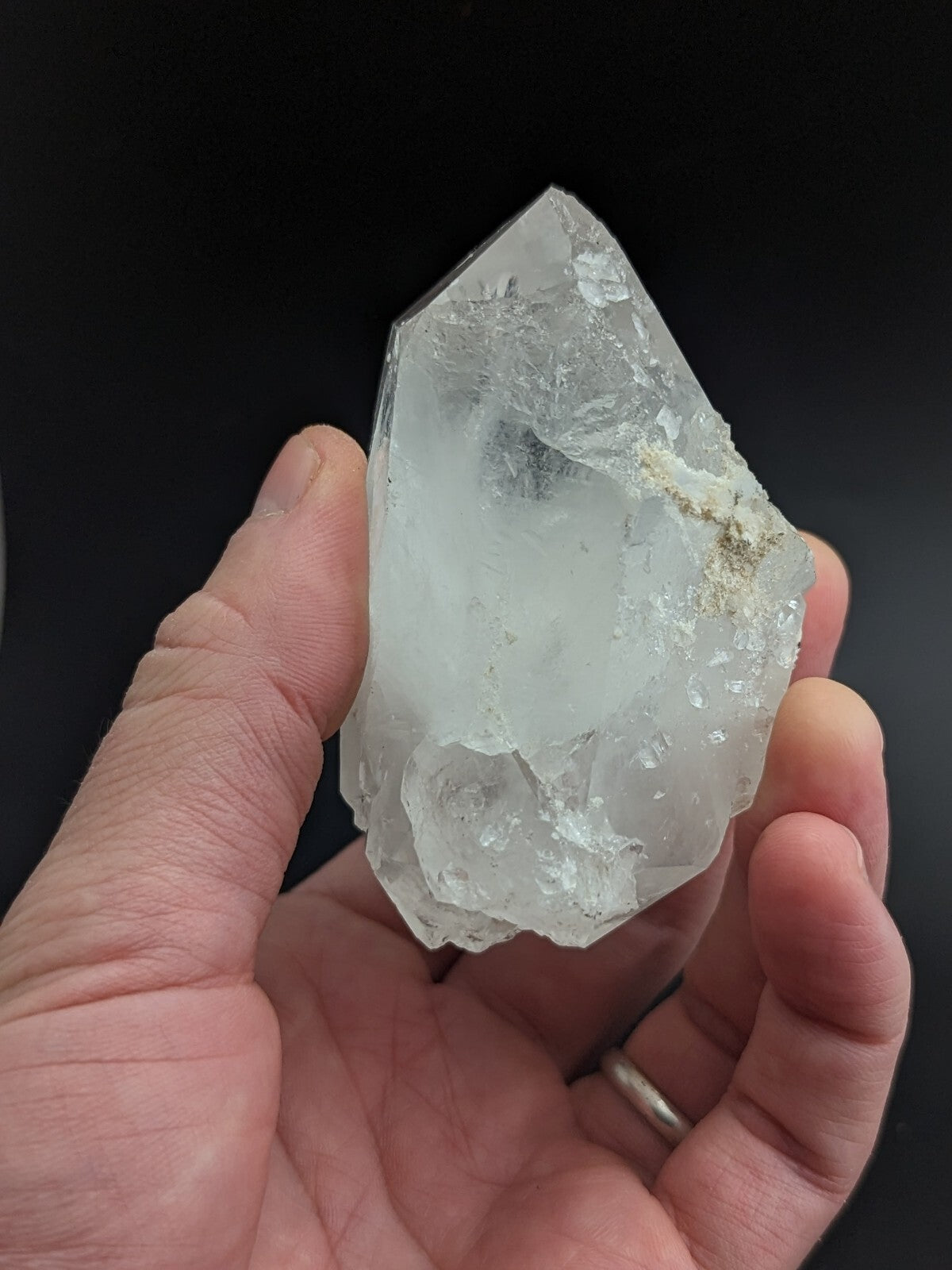 A translucent, clear quartz crystal with a pointed tip and rough, faceted edges.
