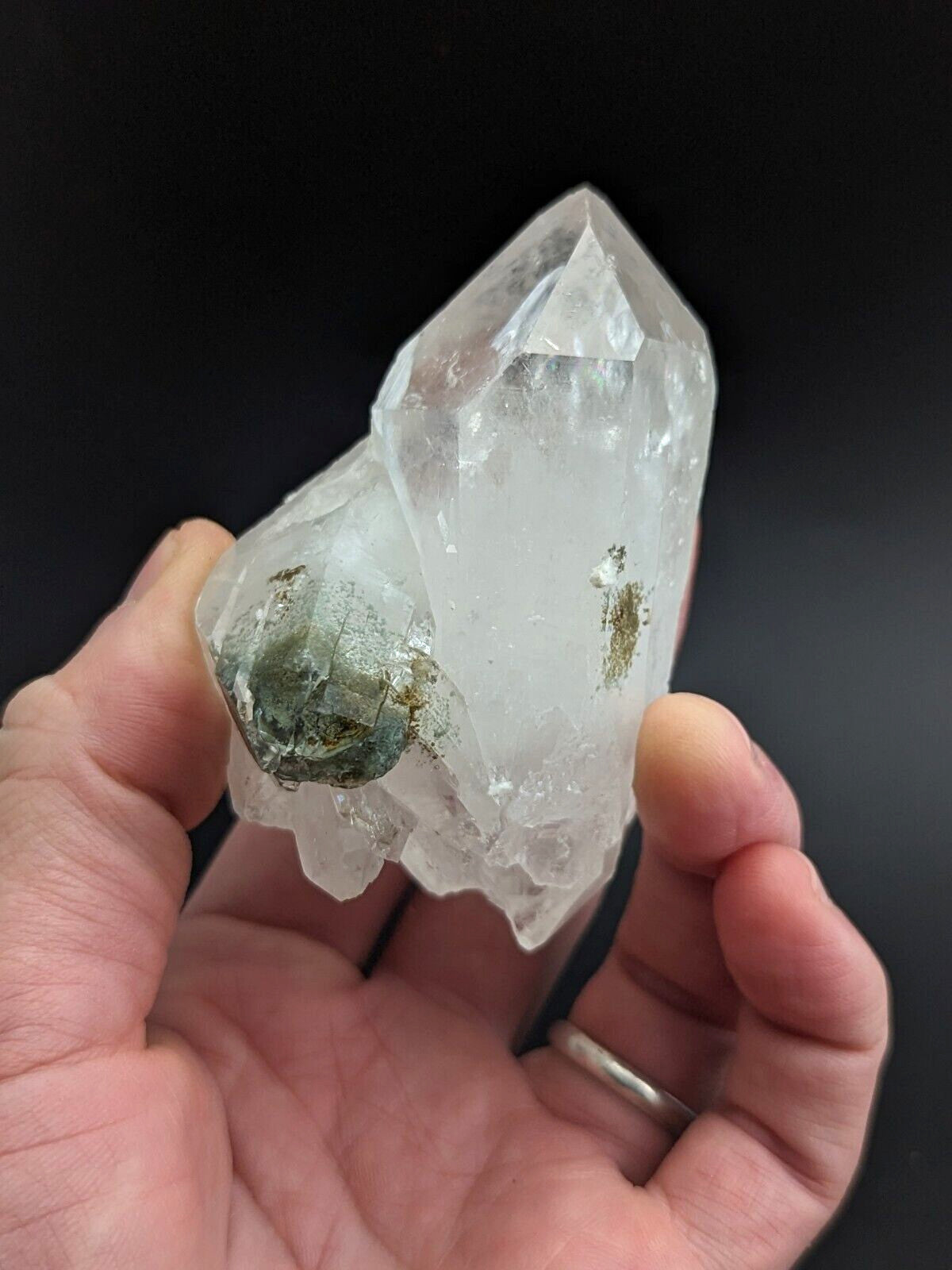 A translucent quartz crystal cluster with a clear, faceted main point and greenish mineral inclusions.