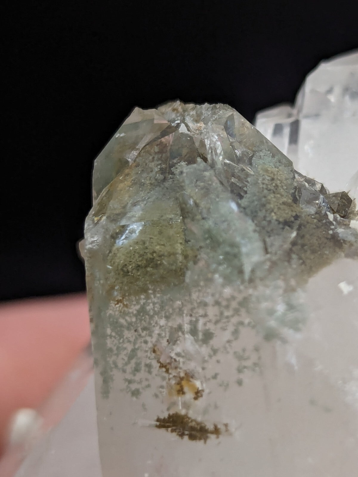 A translucent greenish quartz crystal with natural inclusions and a rough, faceted surface.
