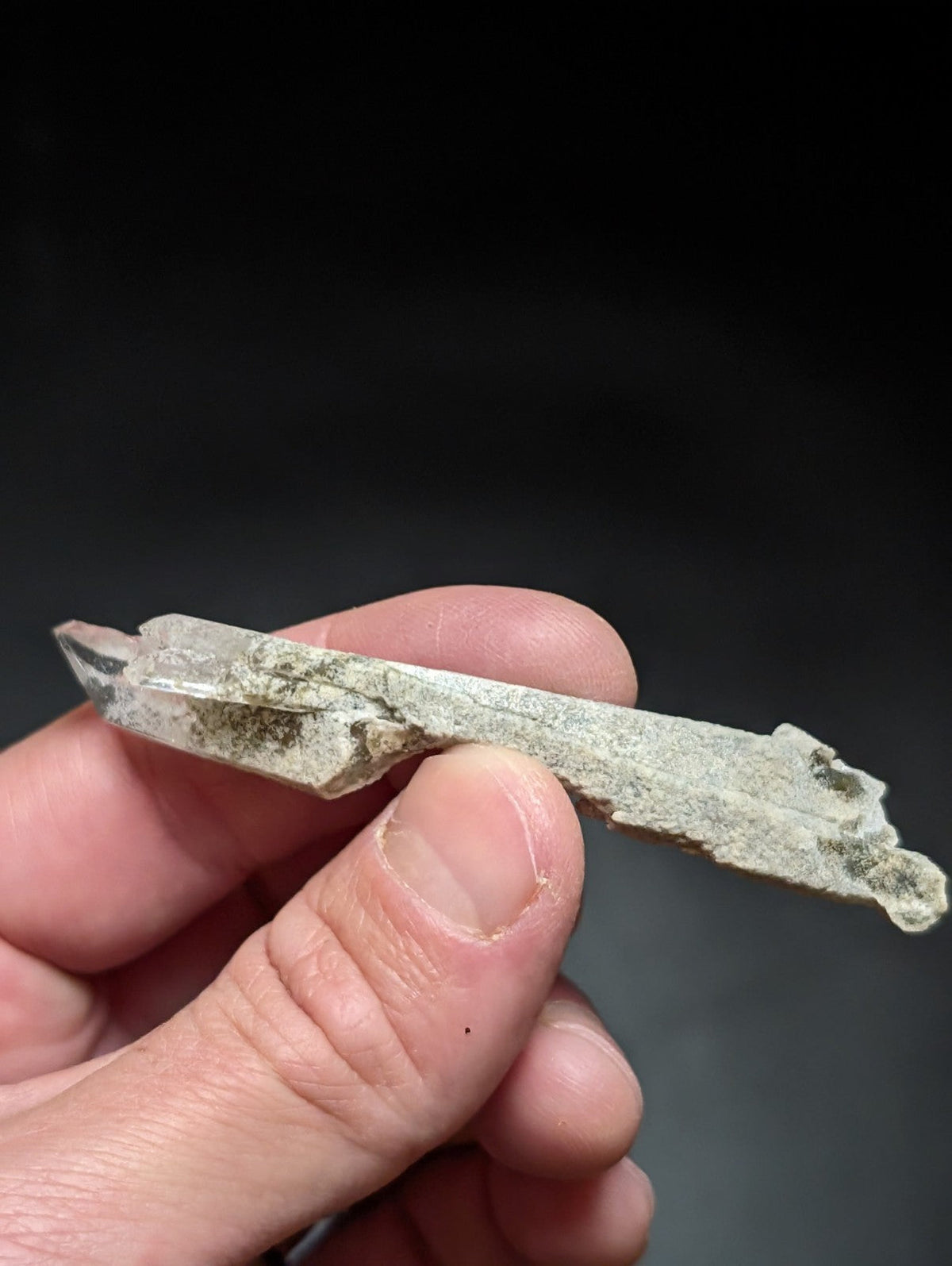 A translucent, pale green quartz crystal with natural striations and minor surface discoloration.