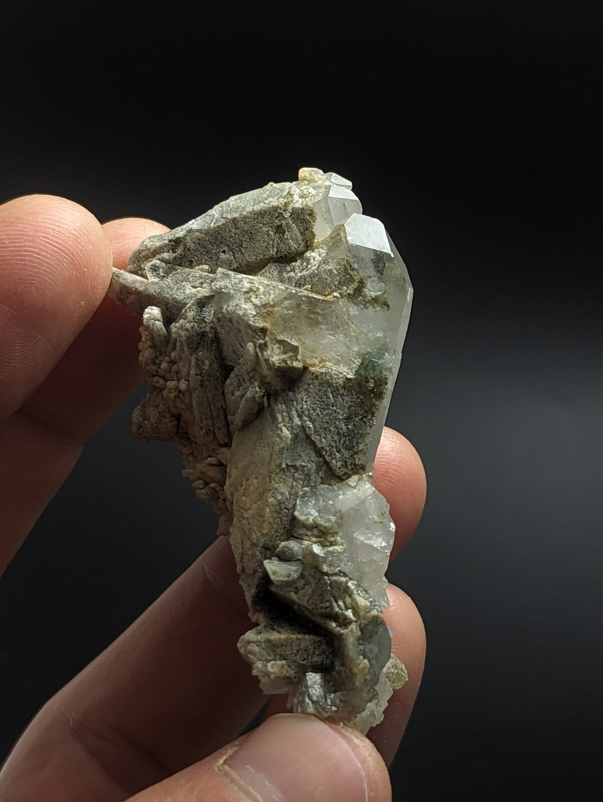 A translucent, pale green quartz crystal cluster with a rough, earthy matrix.