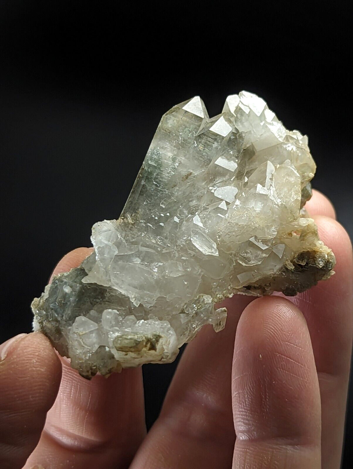 A translucent greenish-white quartz crystal cluster with sharp, faceted points and a rougher base.
