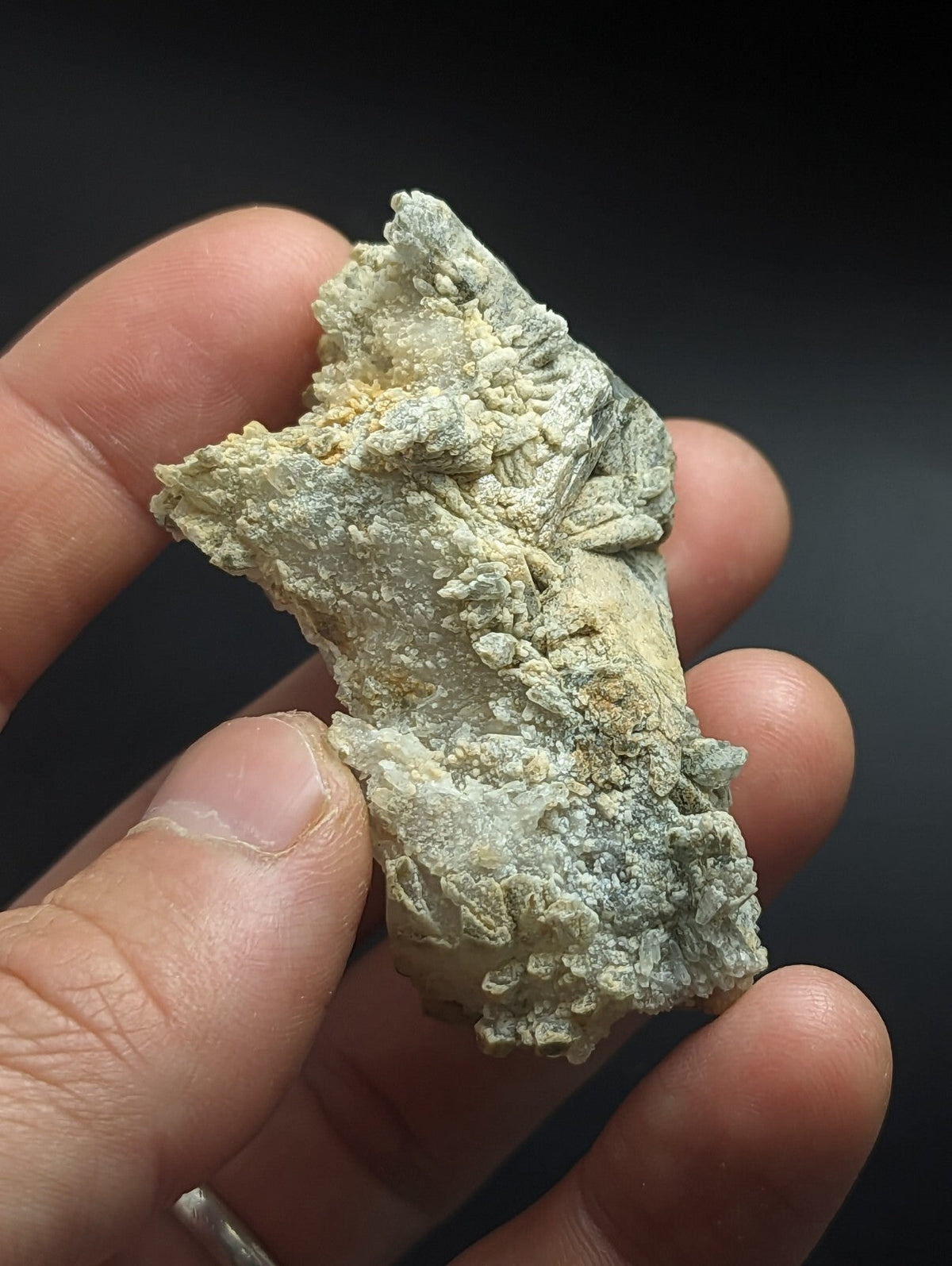 A textured, pale green and white mineral specimen with crystalline formations.