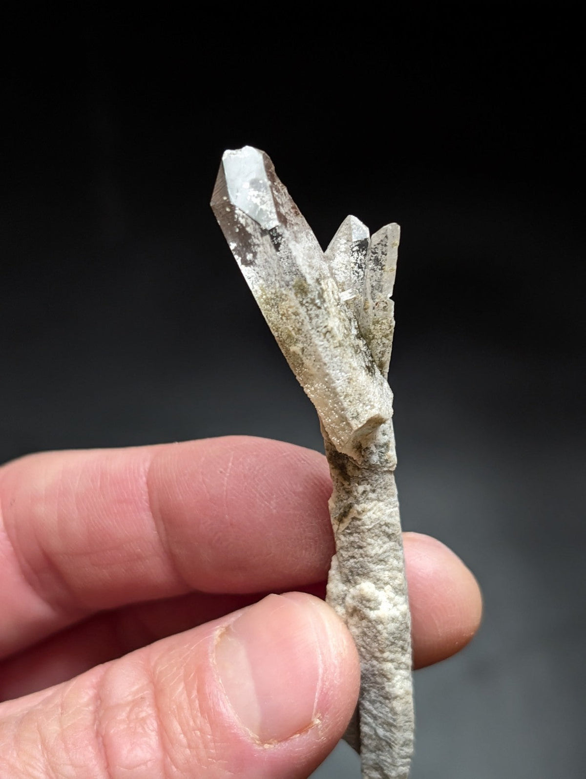 A translucent white quartz crystal cluster with a rough, earthy base and sharp, faceted points.