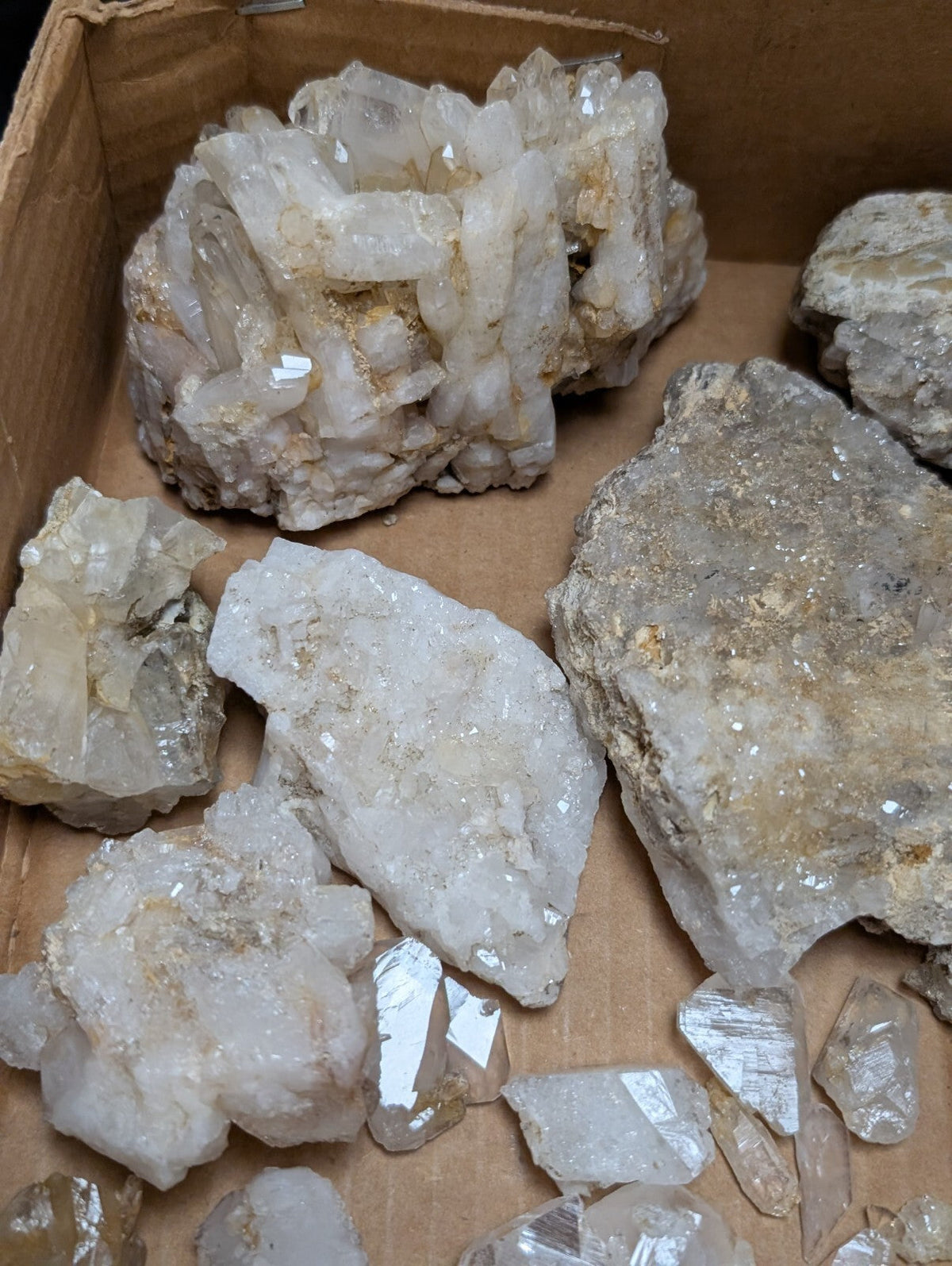 A cluster of translucent white quartz crystals with sharp, faceted edges and some golden mineral inclusions.