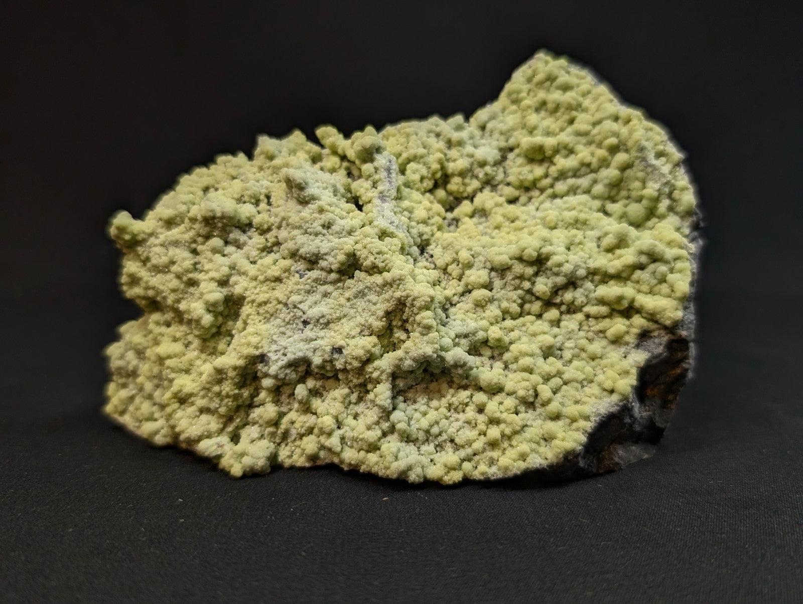 A pale yellow, textured mineral specimen with a rough, bumpy surface and some darker patches.