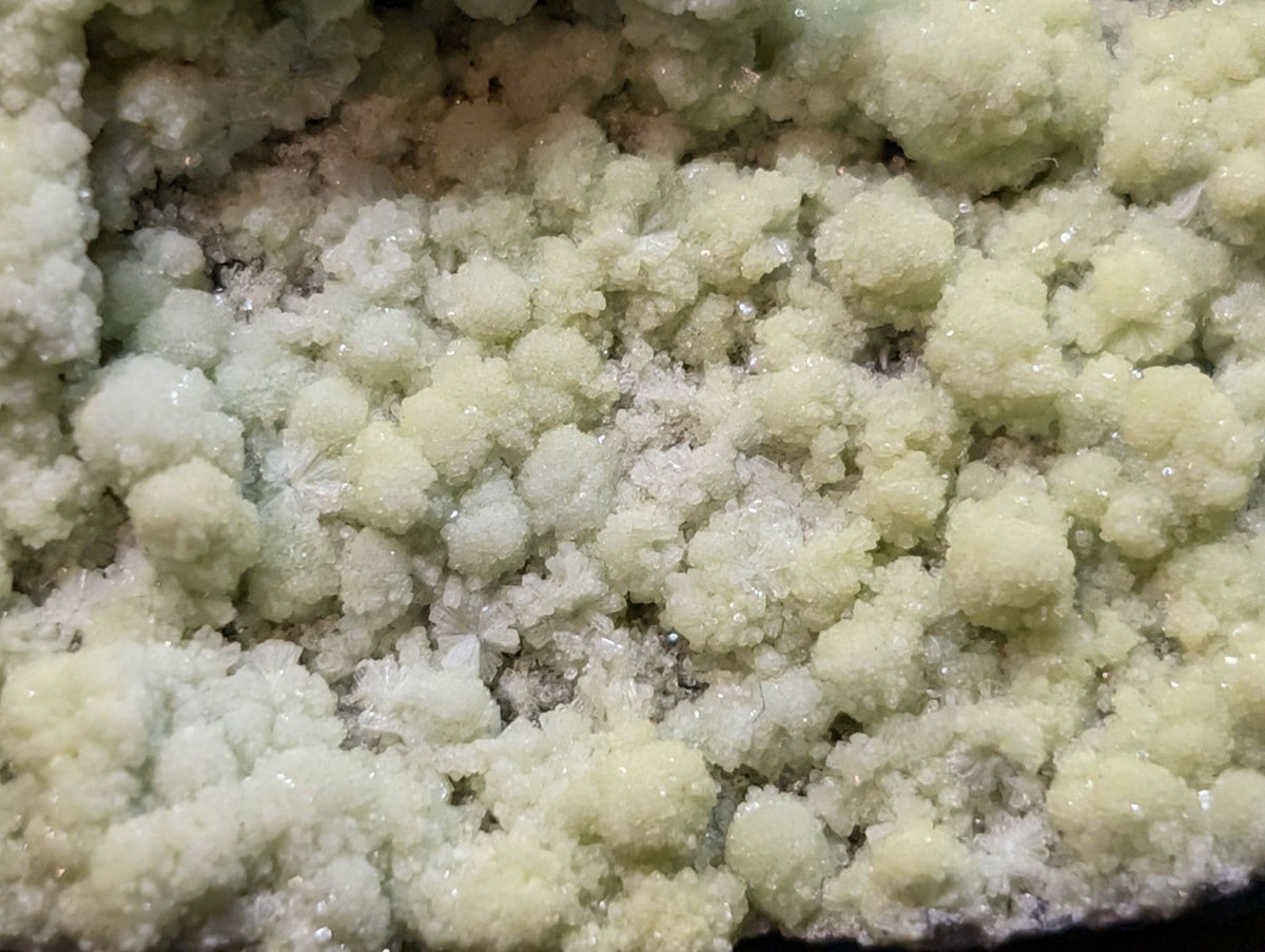 A cluster of pale, crystalline mineral formations with a slightly translucent and glossy surface.