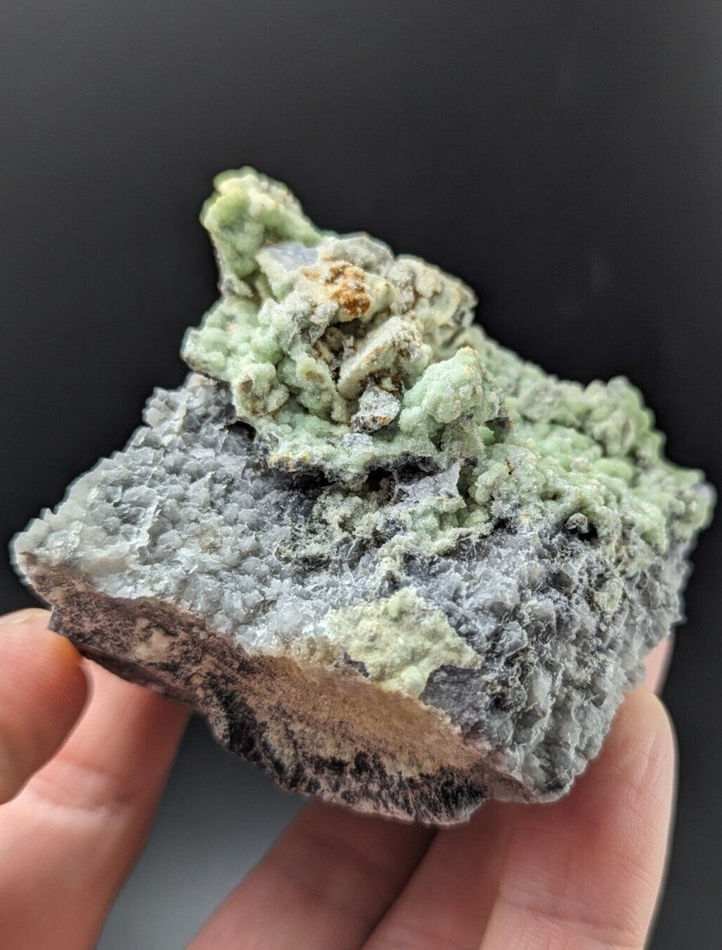 A textured, light green and gray mineral specimen with a rough, crystalline surface.