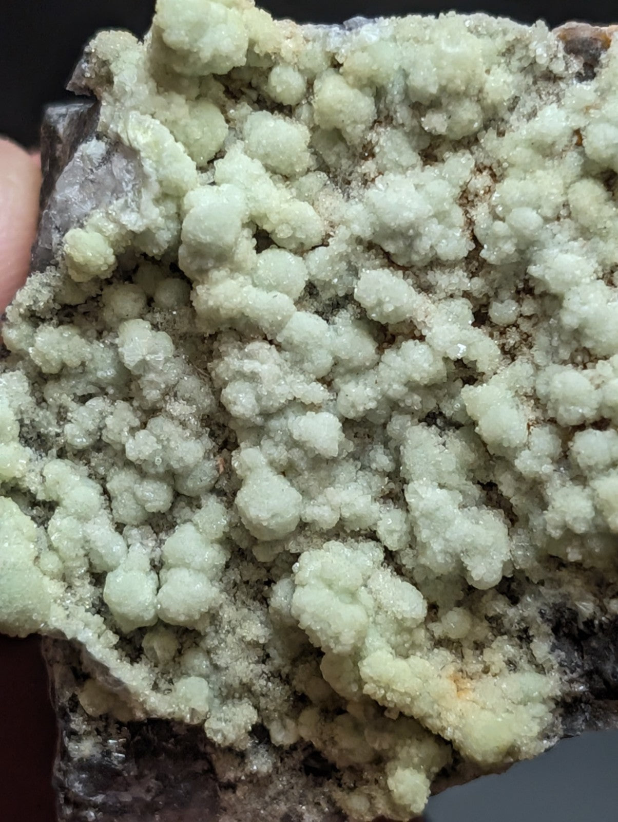 A pale green, crystalline mineral specimen with a textured, bubbly surface.