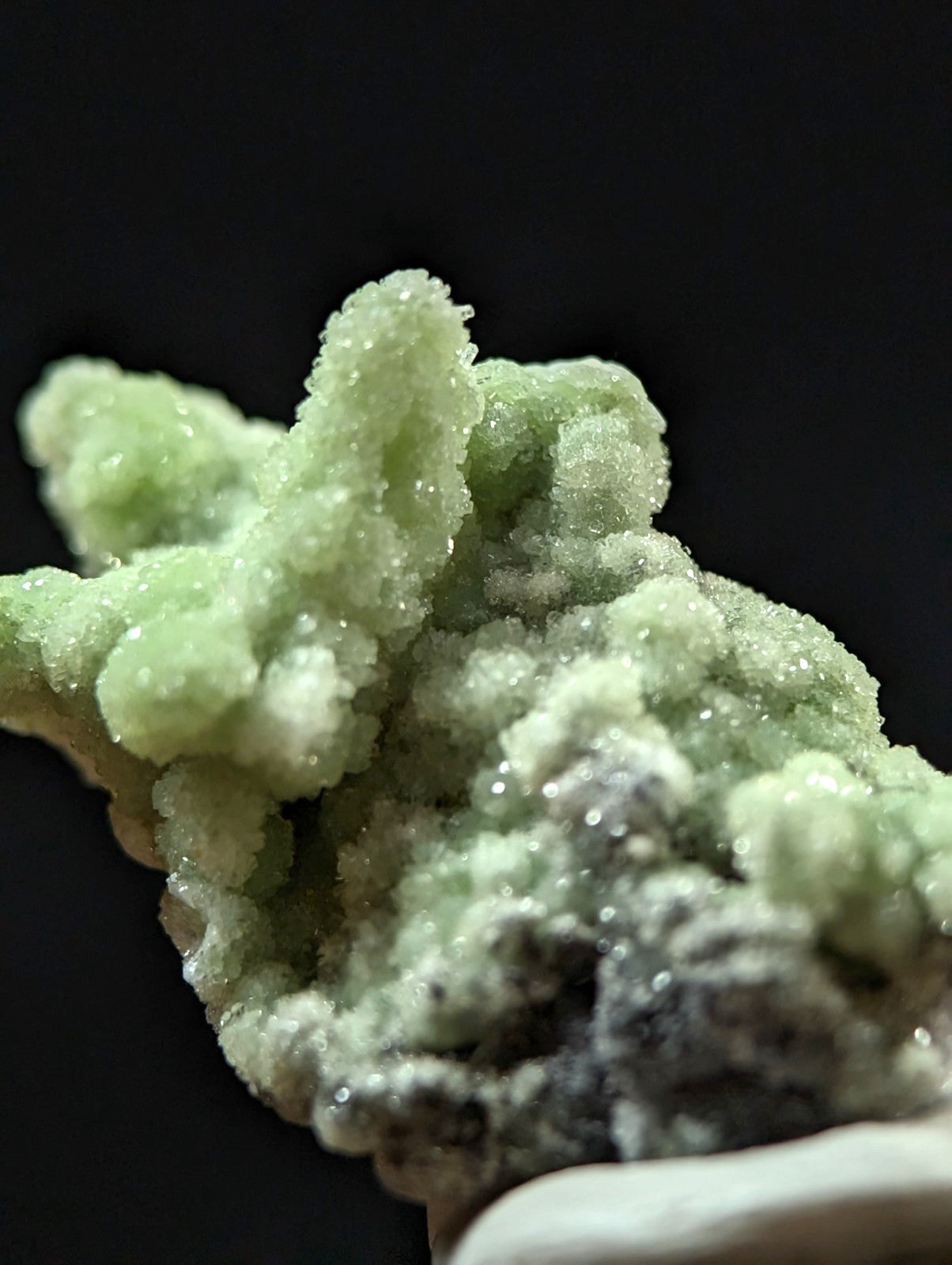 A vibrant green, crystalline mineral specimen with a textured, branching structure and translucent facets.