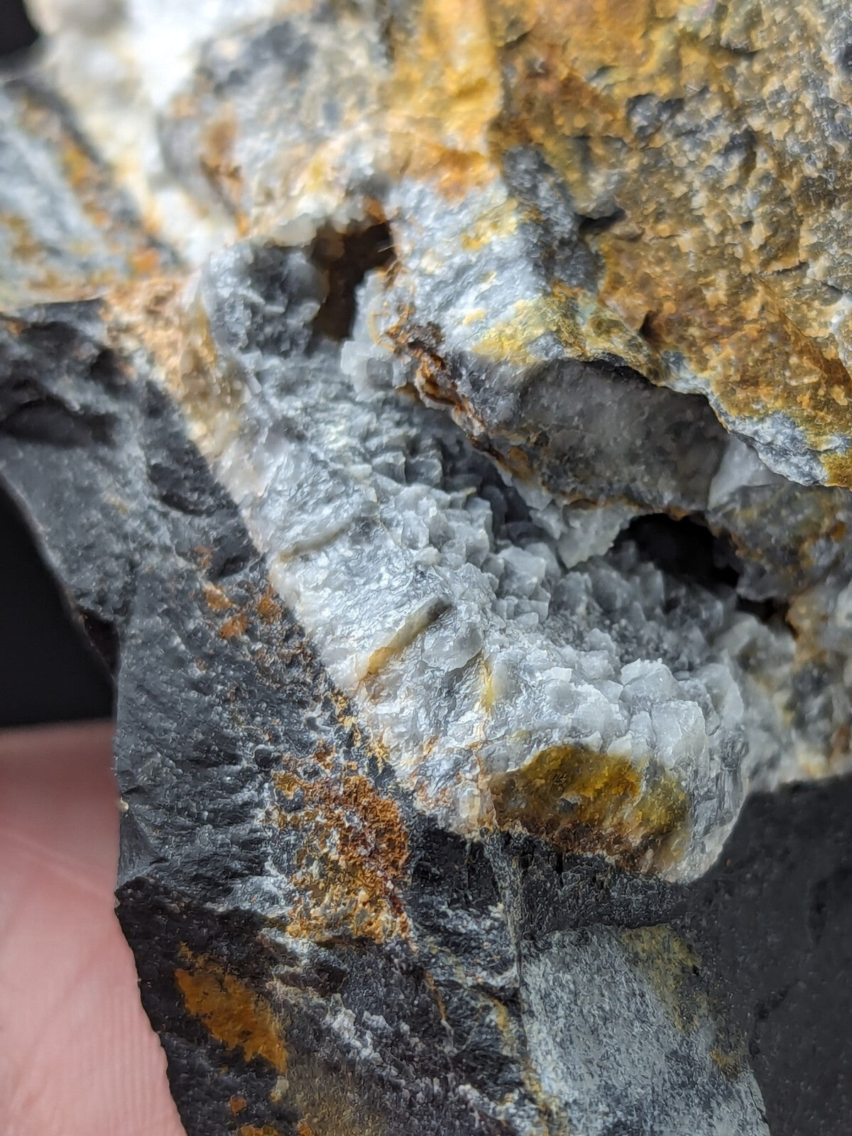 A striking mineral specimen featuring a prominent, crystalline formation with translucent white and gray quartz-like crystals growing from dark, rugged rock matrix accented by patches of orange-yellow oxidation.