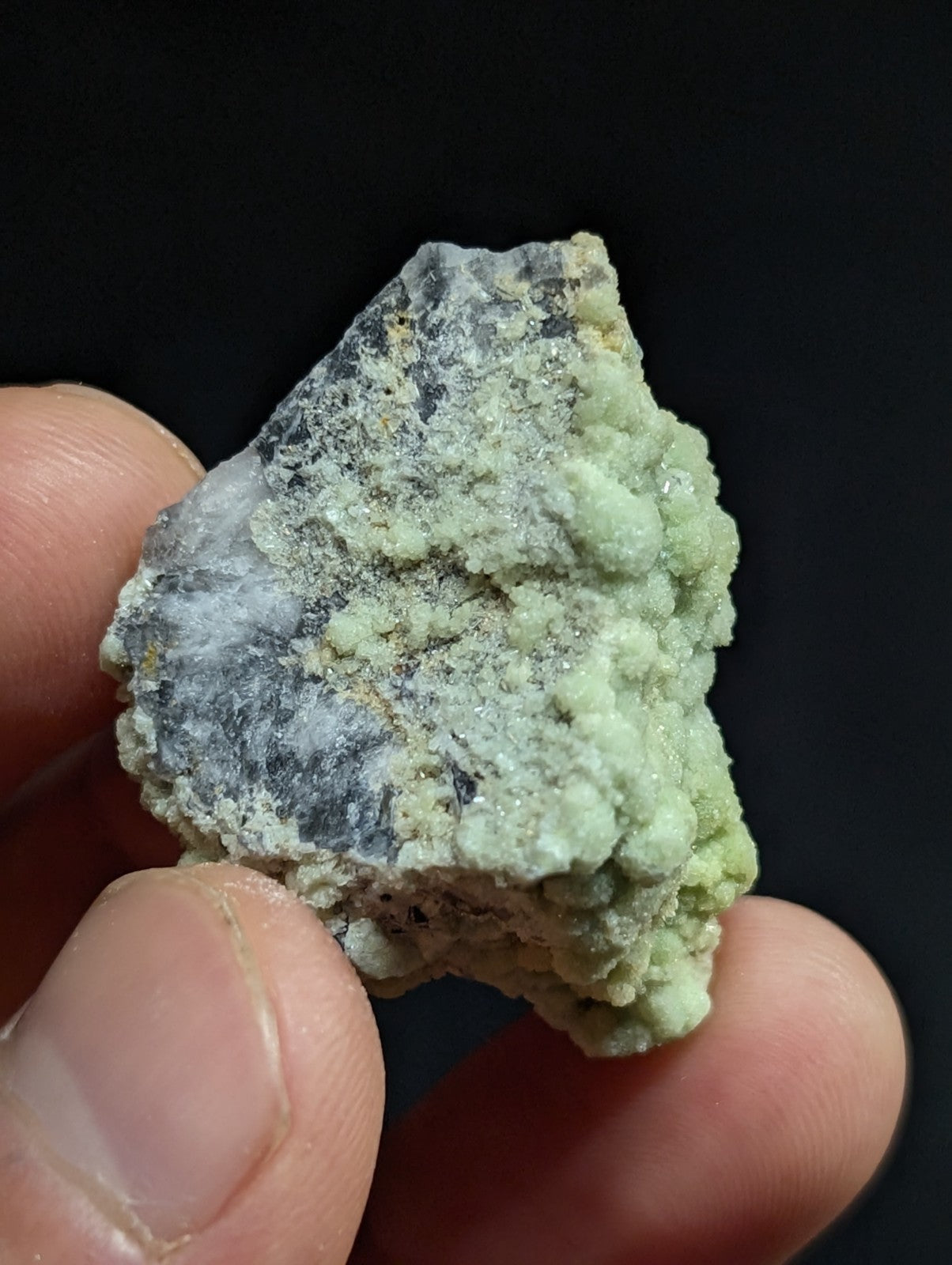 A rough, irregularly shaped mineral specimen with a pale green and grayish surface texture.