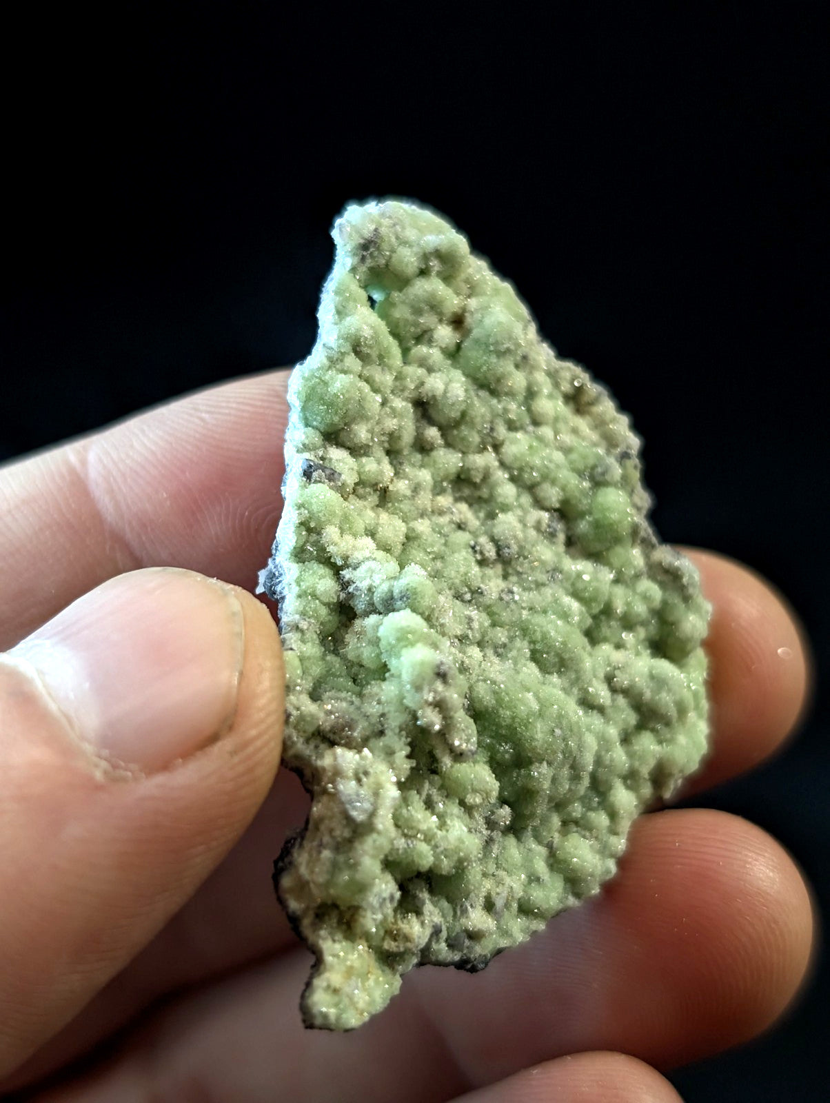 A textured, light green mineral specimen with a bumpy, crystalline surface.