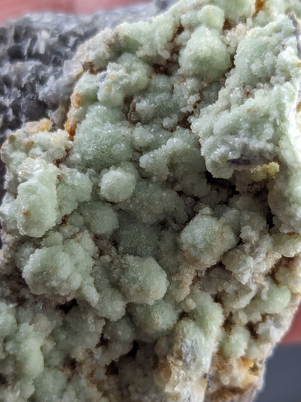 A cluster of pale green, crystalline minerals with a rough, textured surface.