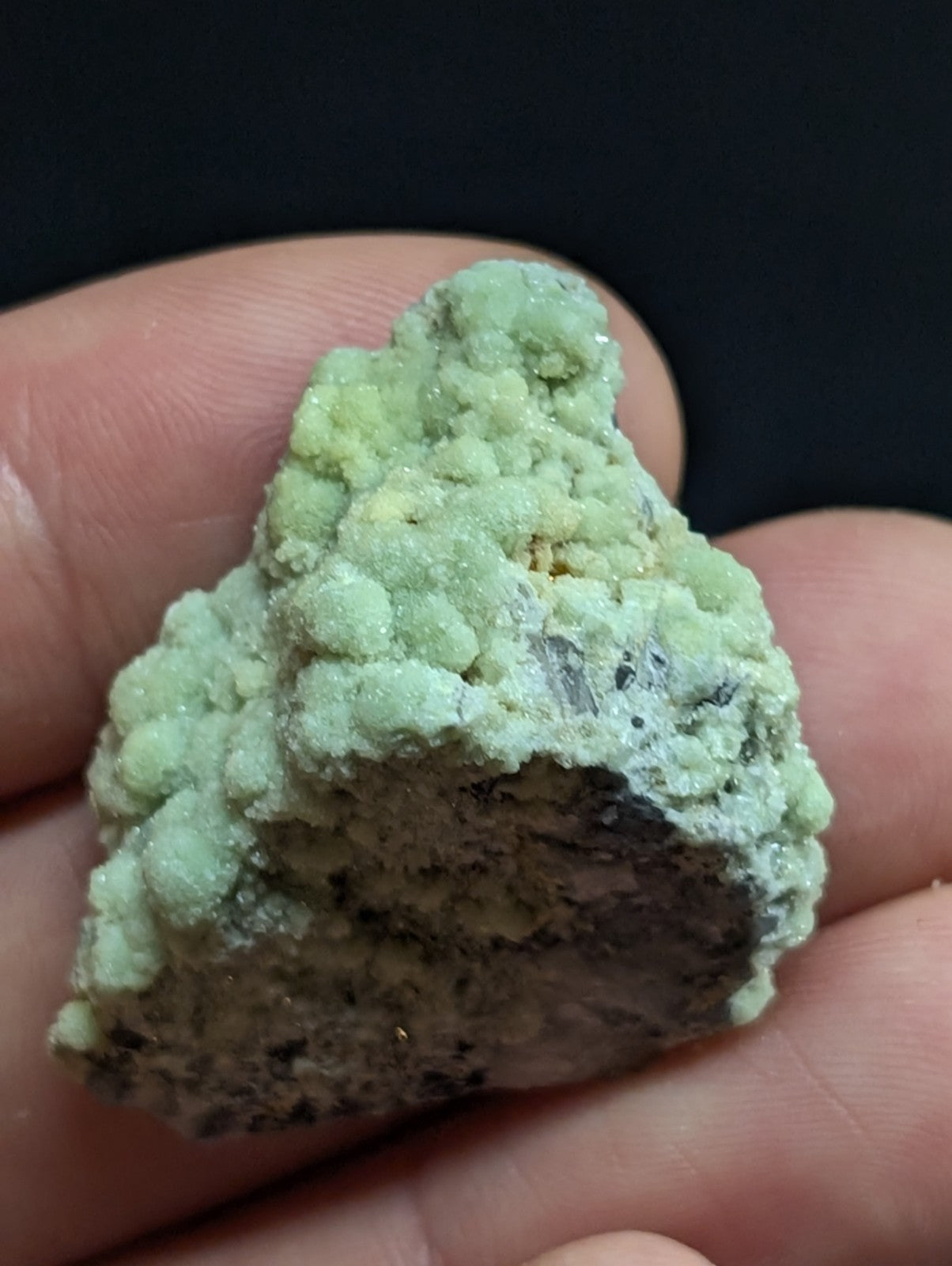 A light green, textured mineral specimen with a rough, bumpy surface and darker grayish base.