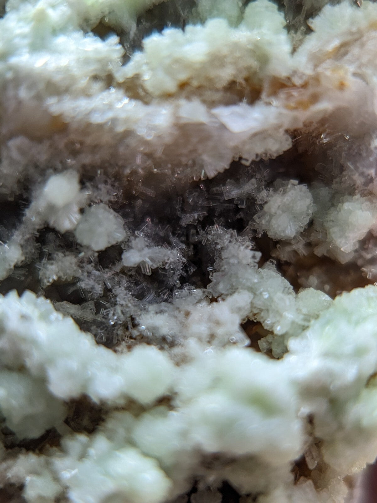 A close-up view of a mineral specimen featuring intricate, crystalline formations with translucent white and pale green hues.