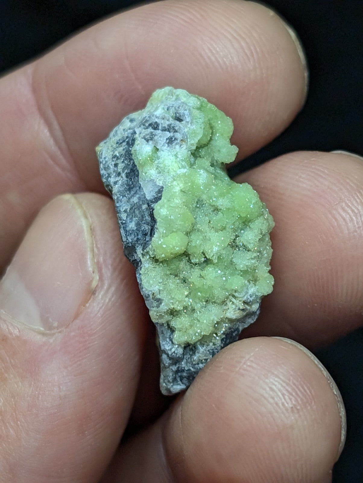 A rough, light green mineral specimen with a crystalline texture and grayish matrix.