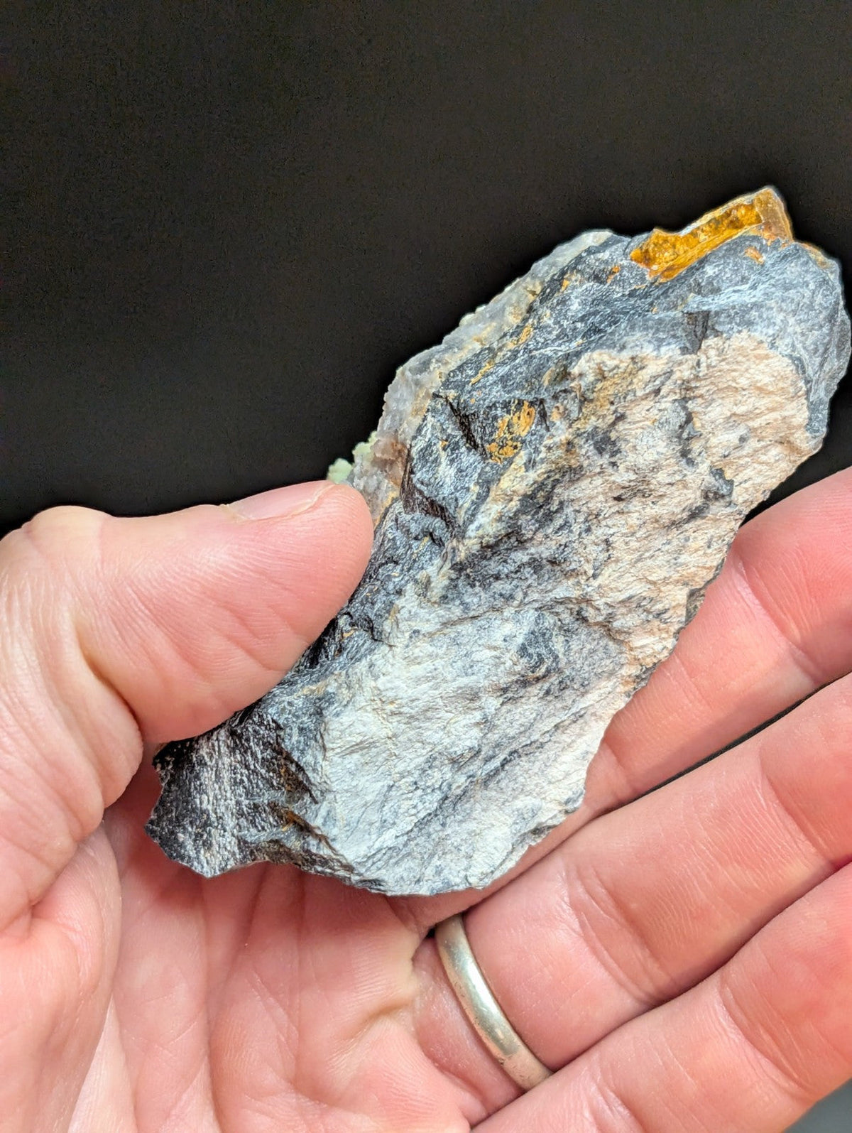 A rugged, grayish-blue rock with patches of golden-yellow mineral inclusions.