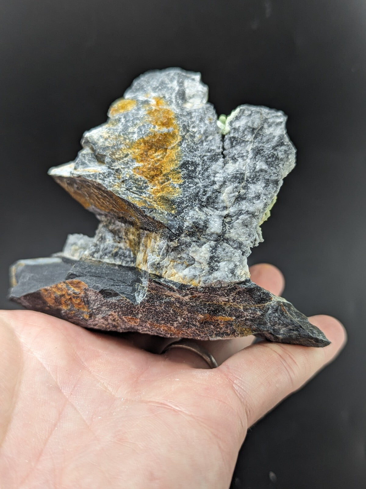 A rugged, multi-toned mineral specimen featuring a grayish base with patches of vibrant yellow and subtle green veining.