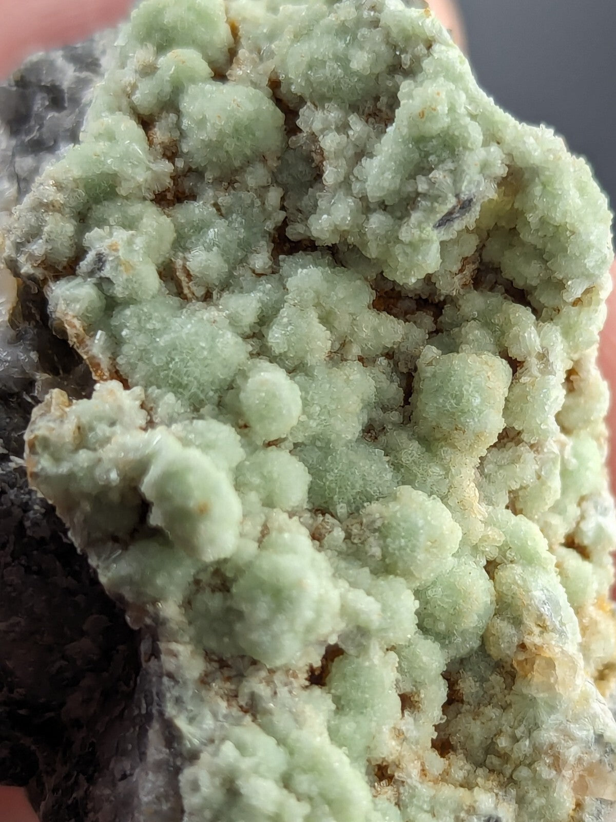 A cluster of pale green, crystalline minerals with a rough, textured surface.