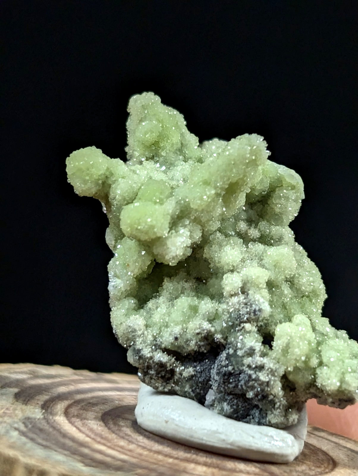 A vibrant green, crystalline mineral specimen with a textured, branching structure and sparkling facets.
