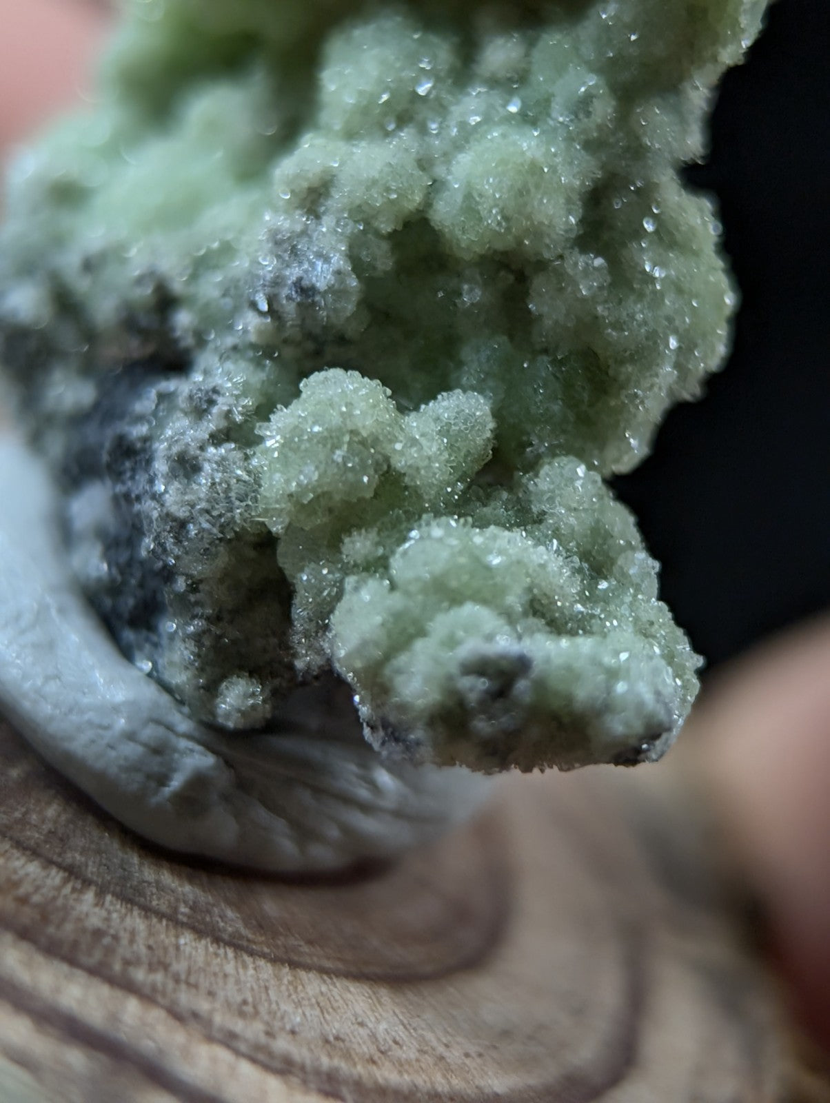 A textured, light green crystalline mineral specimen with a rough, clustered surface and subtle grayish undertones.