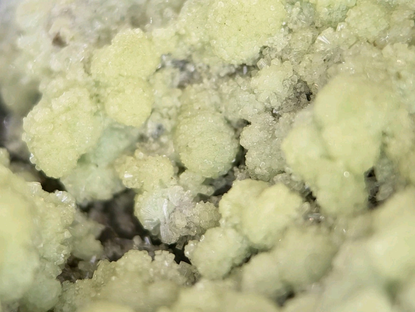 Pale green, crystalline mineral formations with a rough, textured surface.