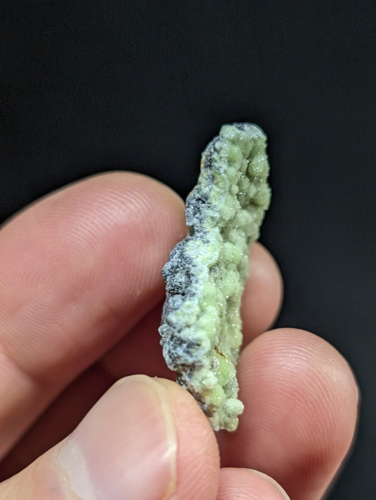 A textured, pale green mineral specimen with a rough, bumpy surface and subtle grayish patches.