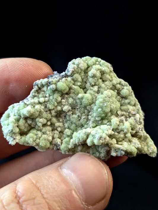 A textured, light green mineral specimen with a bumpy, crystalline surface and subtle white veining.