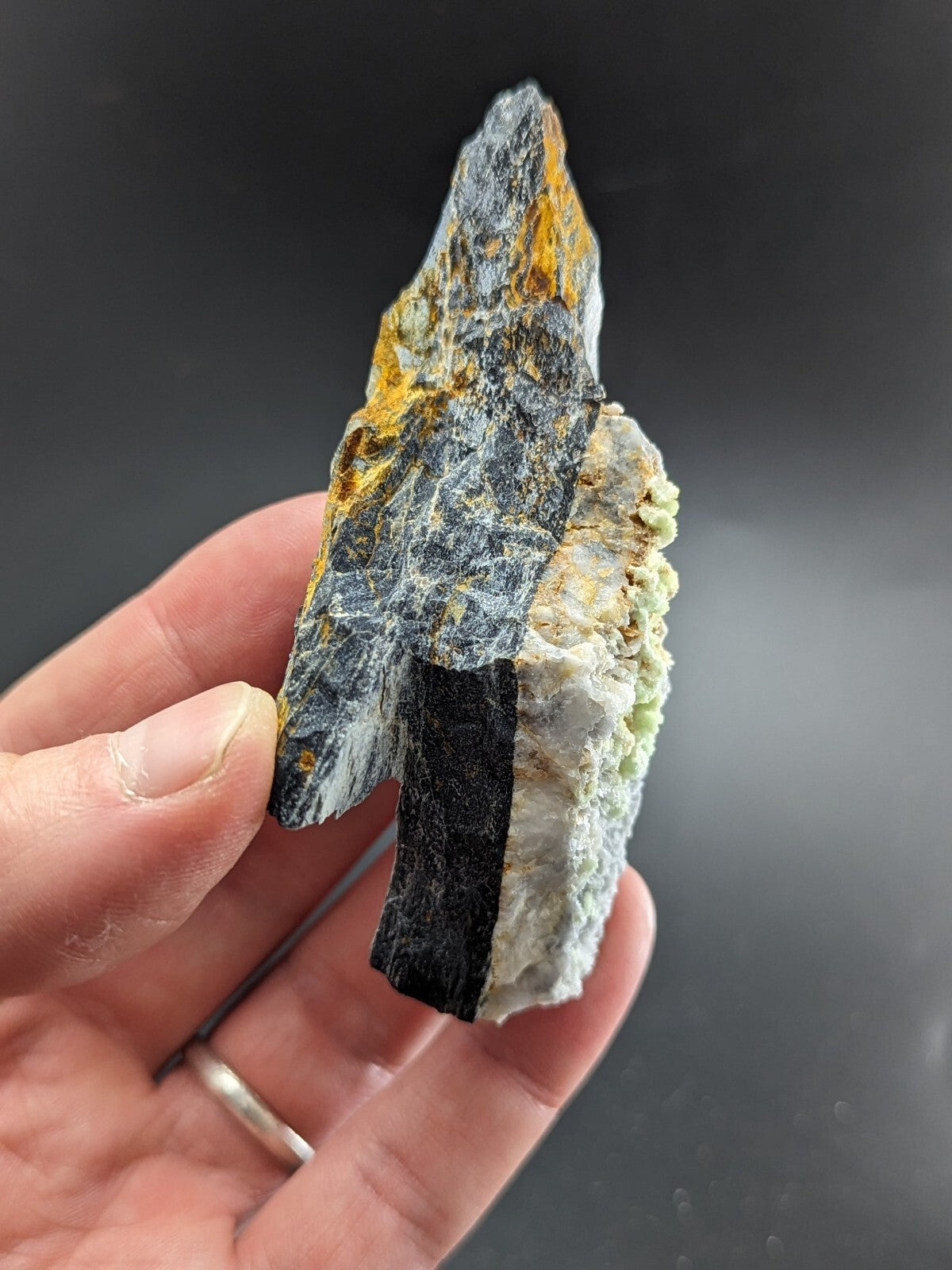 A striking black, gray, and yellow mineral specimen with a jagged edge.
