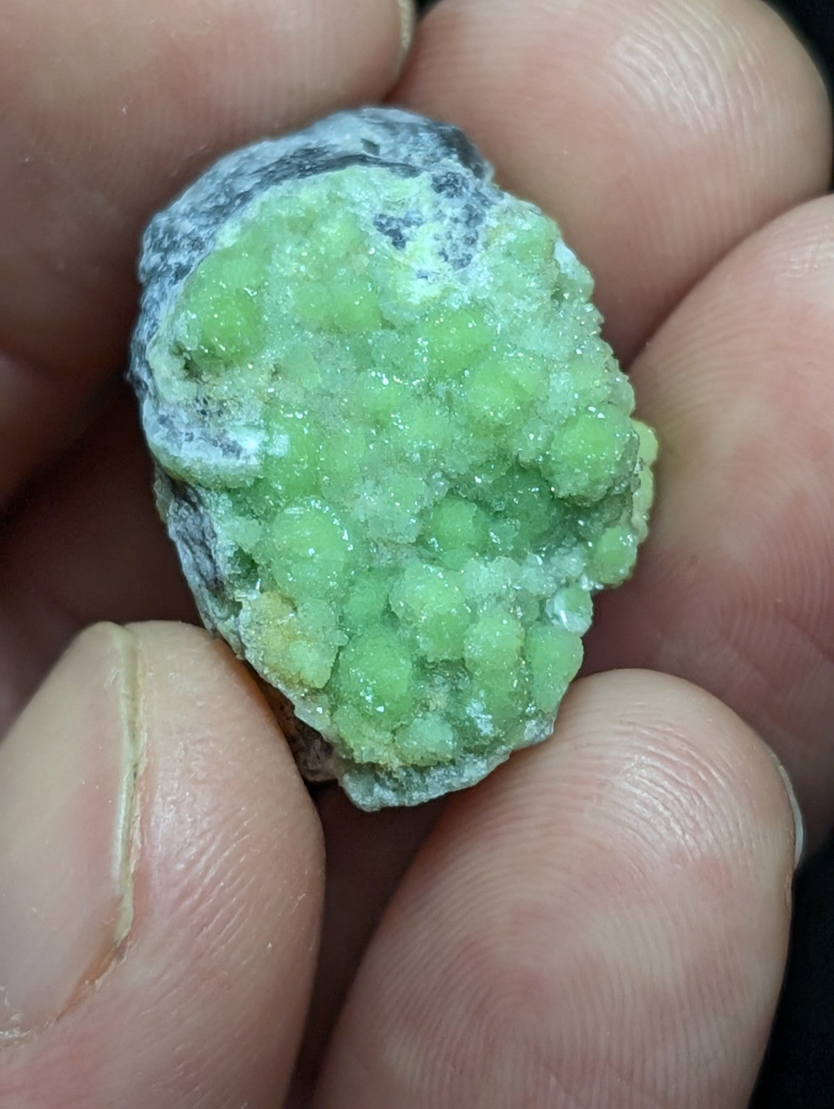 A vibrant green, crystalline mineral specimen with a rough, textured surface and embedded white veining.