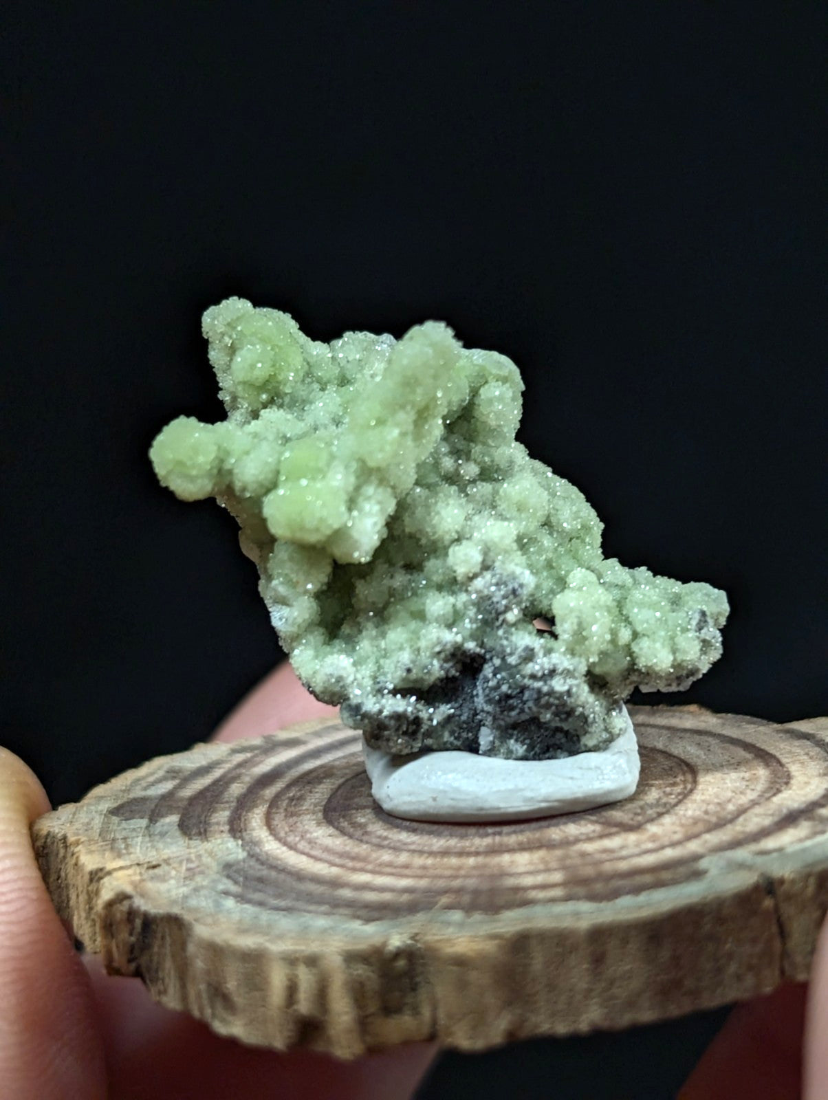 A vibrant green, crystalline mineral specimen with a textured, branching structure and subtle white highlights.