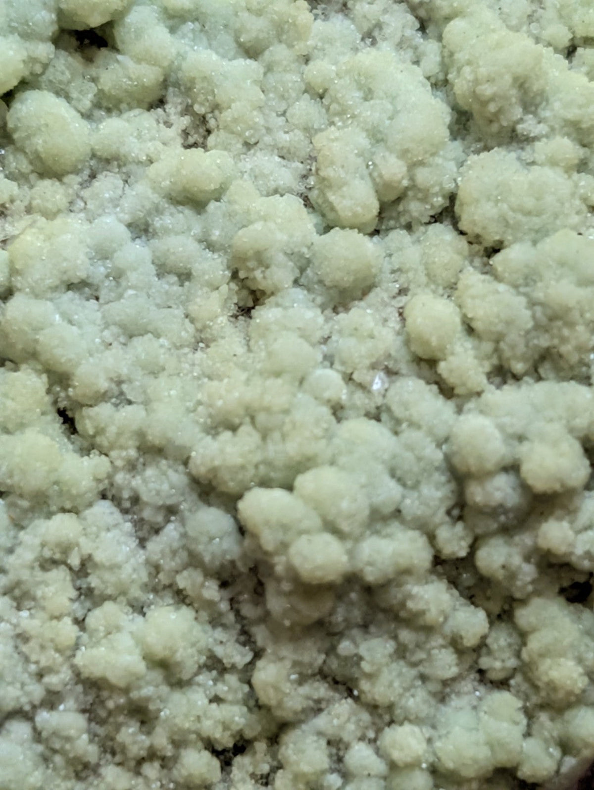 A cluster of pale green, crystalline rock formations with a rough, granular texture.
