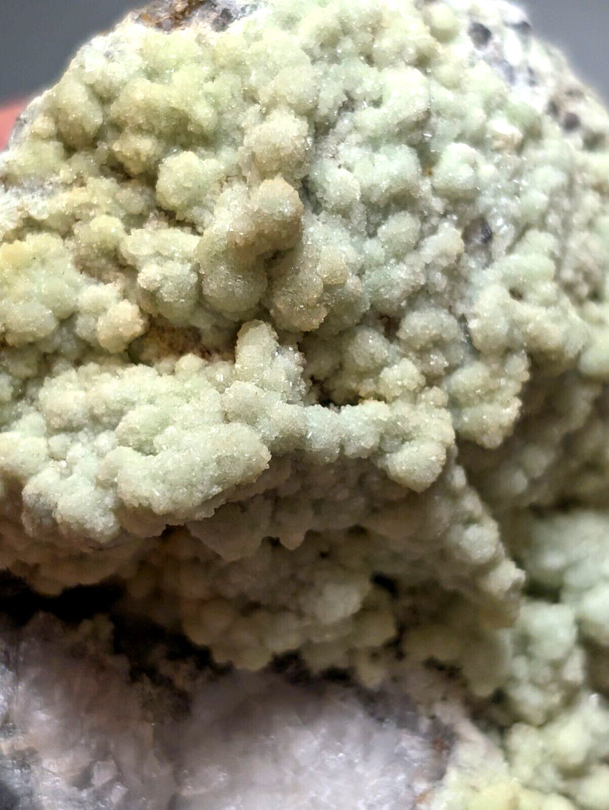 A pale green, crystalline mineral specimen with a textured, bumpy surface.