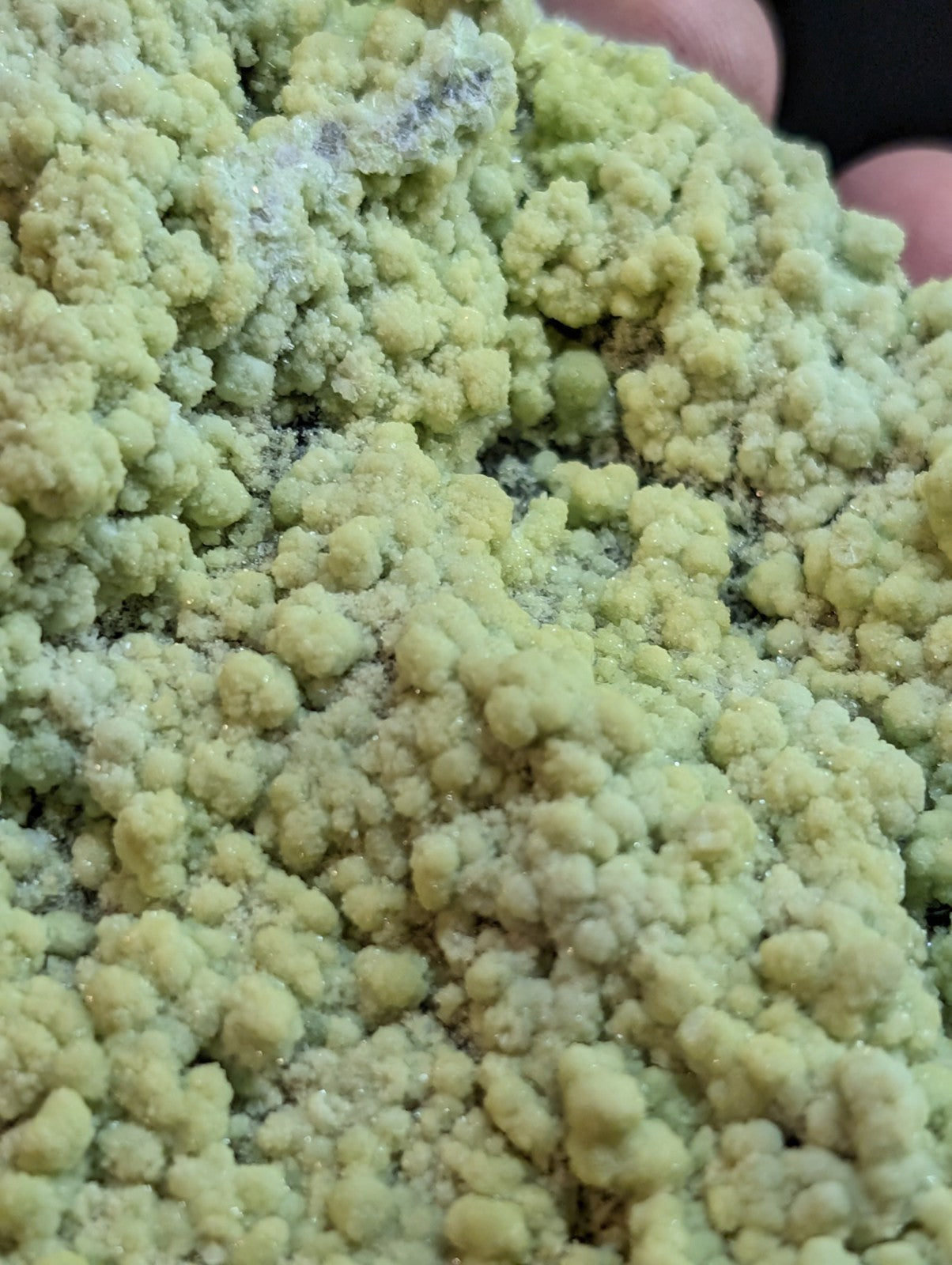 A cluster of pale green, crystalline mineral formations with a rough, textured surface.