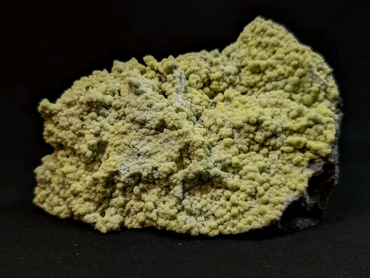 A pale yellow, textured mineral specimen with a rough, bumpy surface and some darker patches.