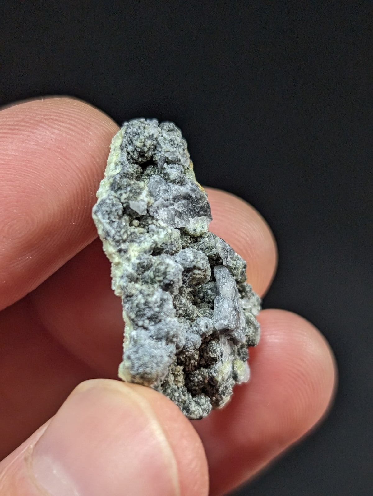 A rough, irregularly shaped mineral specimen with a mottled gray and white surface texture.